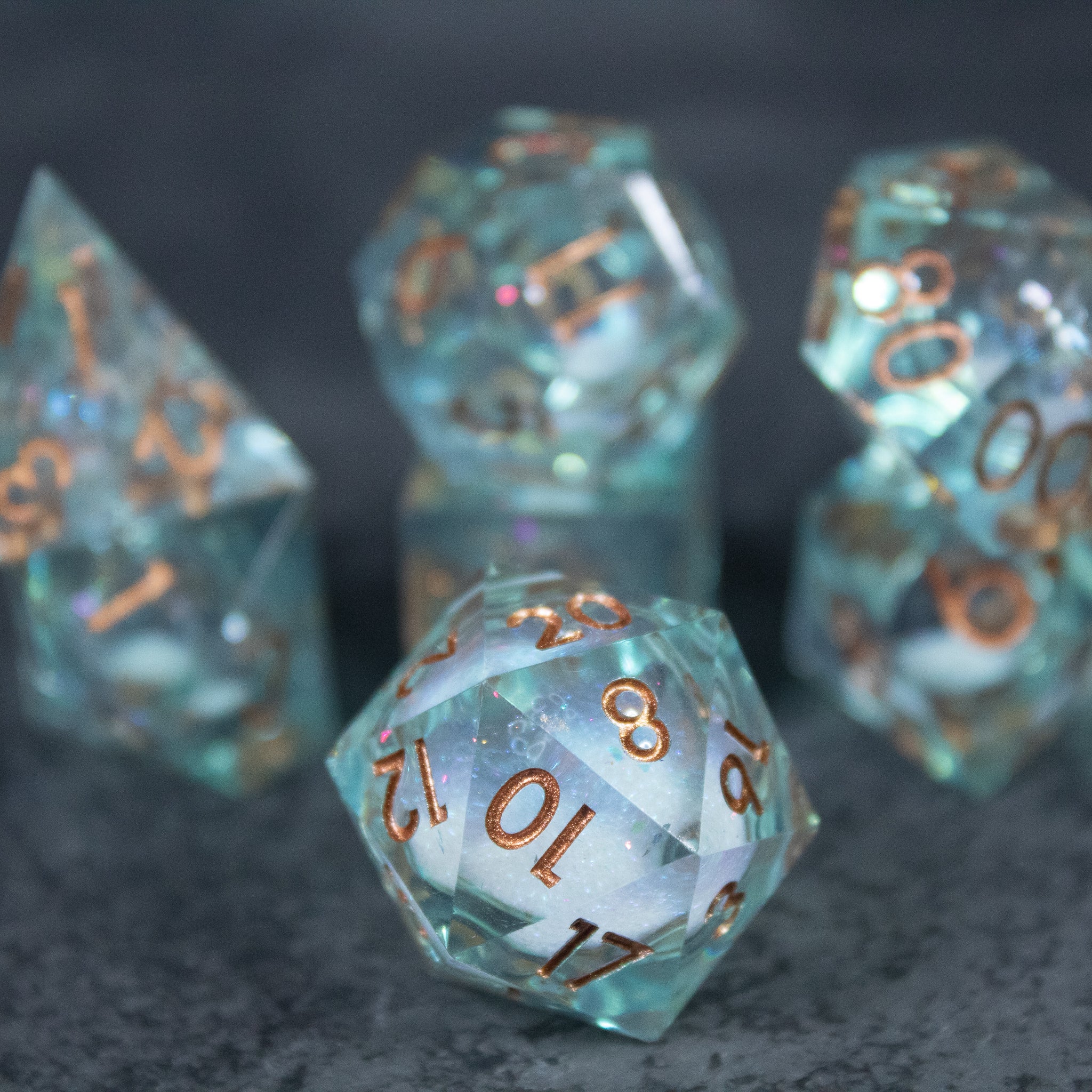 Will o' Wisp Liquid Core Dice Set - Transparent blue liquid core 20-sided dice with sharp edges and copper numbers.