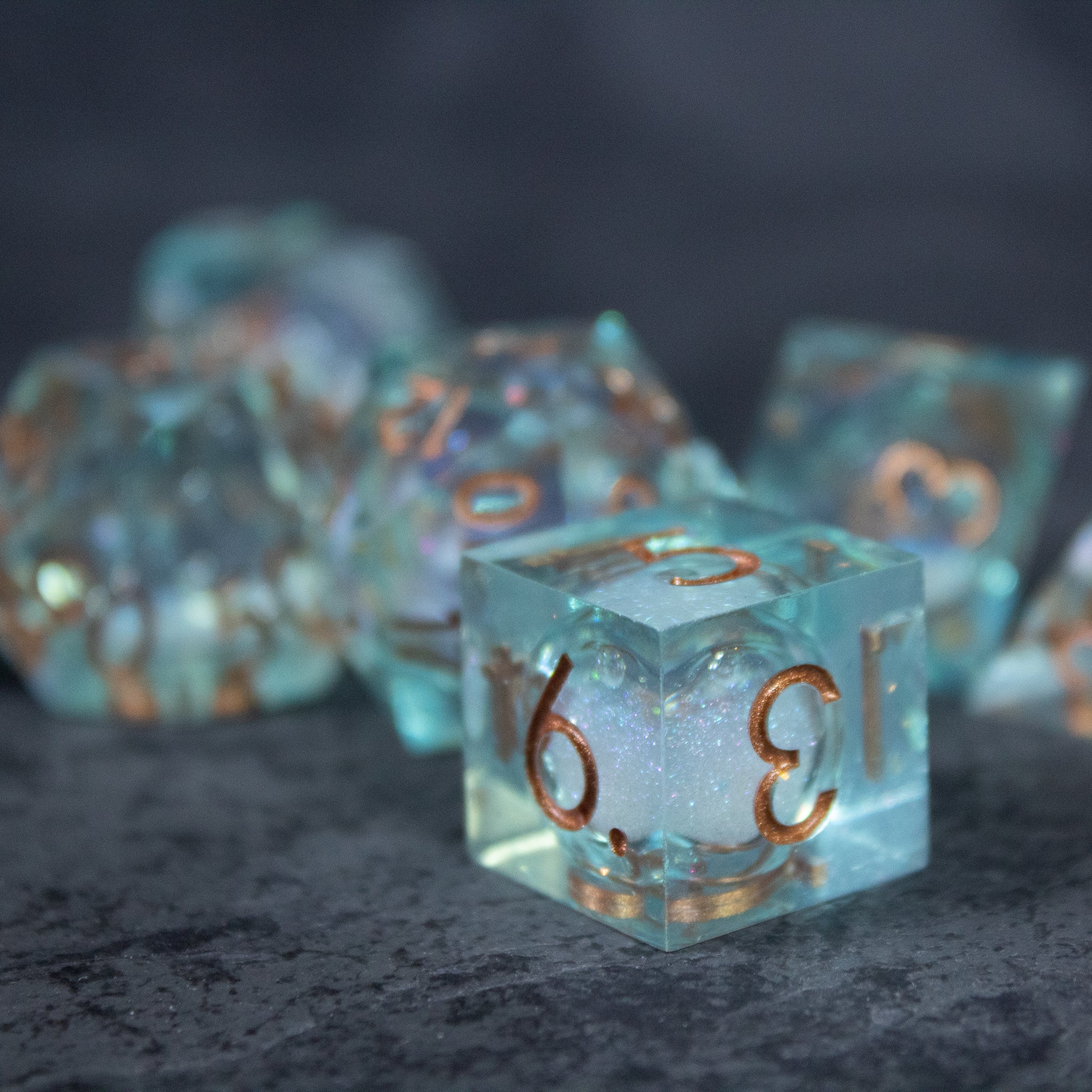 Will o' Wisp Liquid Core Dice Set - Set of translucent blue polyhedral dice with sharp edges and gold liquid core details.