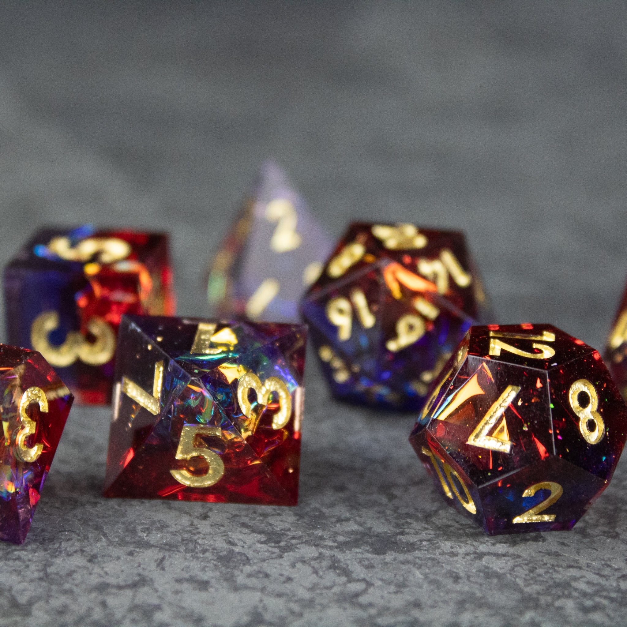 Electromancer Dice Set - Blue and red sharp-edged polyhedral dice with gold numbering on gray surface.