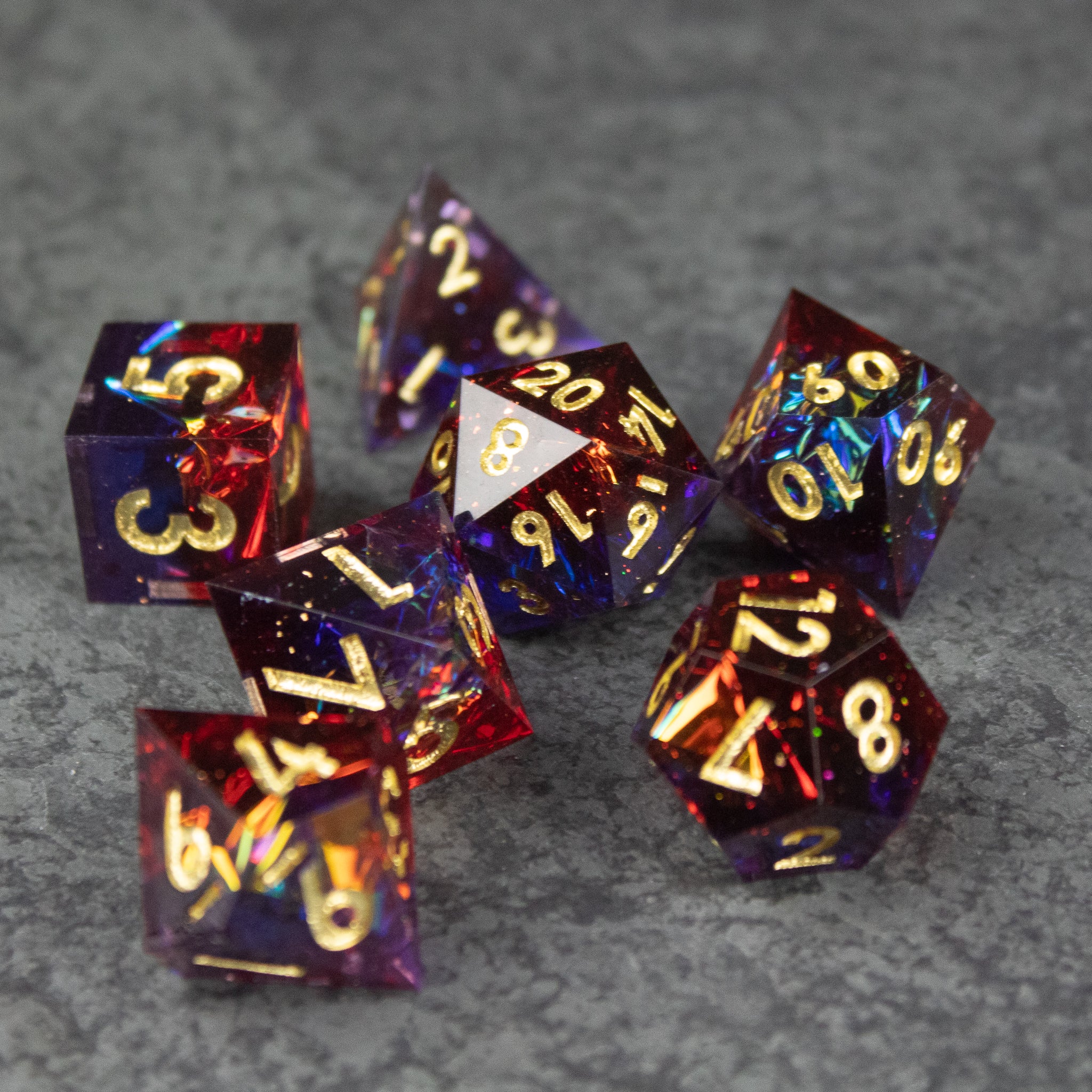 Electromancer Dice Set - Set of translucent red and blue sharp-edge polyhedral dice with gold numbering.