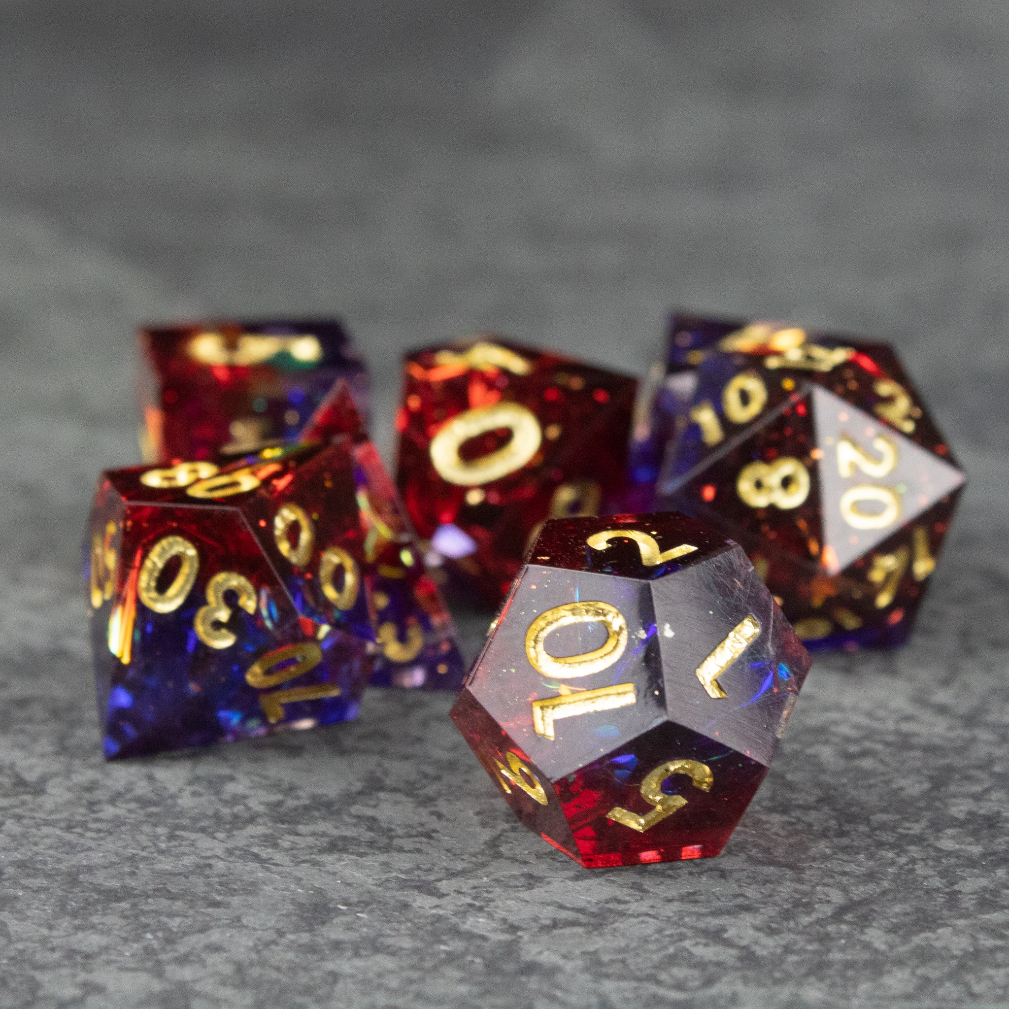 Electromancer Dice Set - Set of seven sharp-edged polyhedral dice in translucent blue and red with gold numbers.