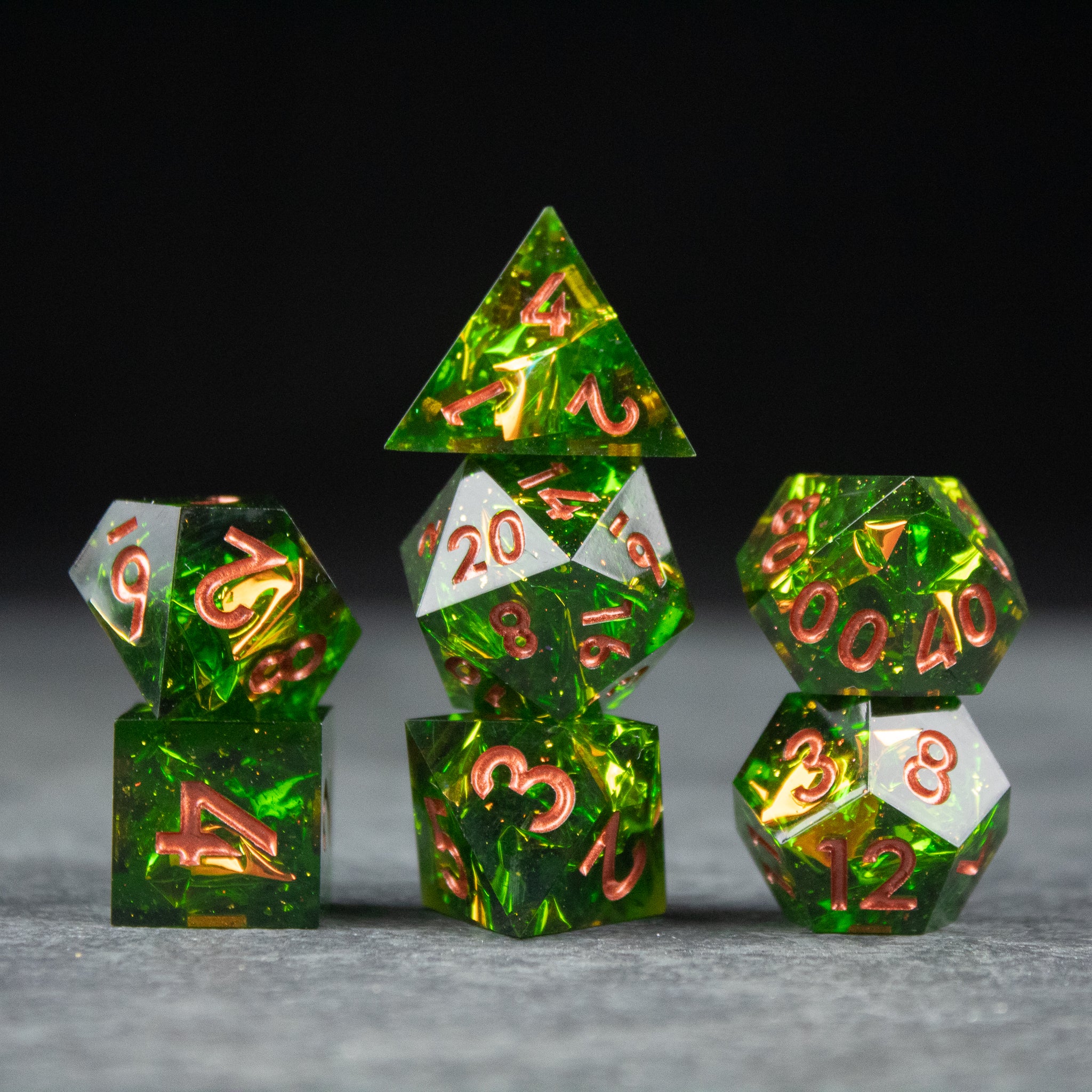 Venom Dice Set - Set of sharp-edged green translucent dice with red numbers, featuring 4-sided to 20-sided dice arranged on gray surface.