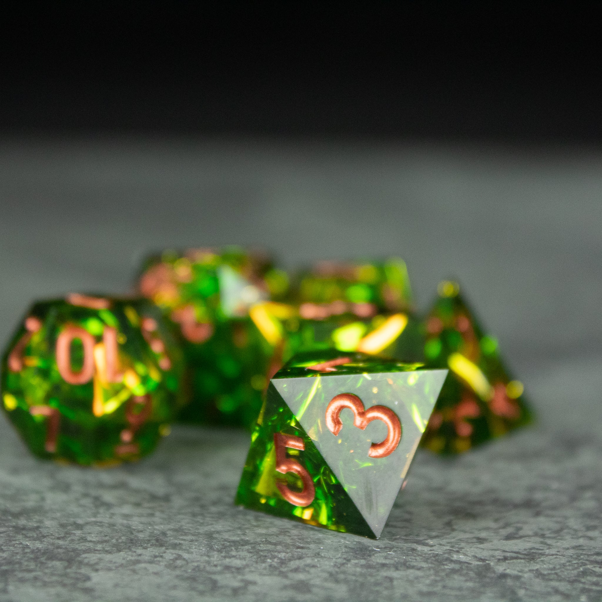 Venom Dice Set - Set of sharp-edged translucent green dice with metallic orange numbers, including a 4-sided die in front.