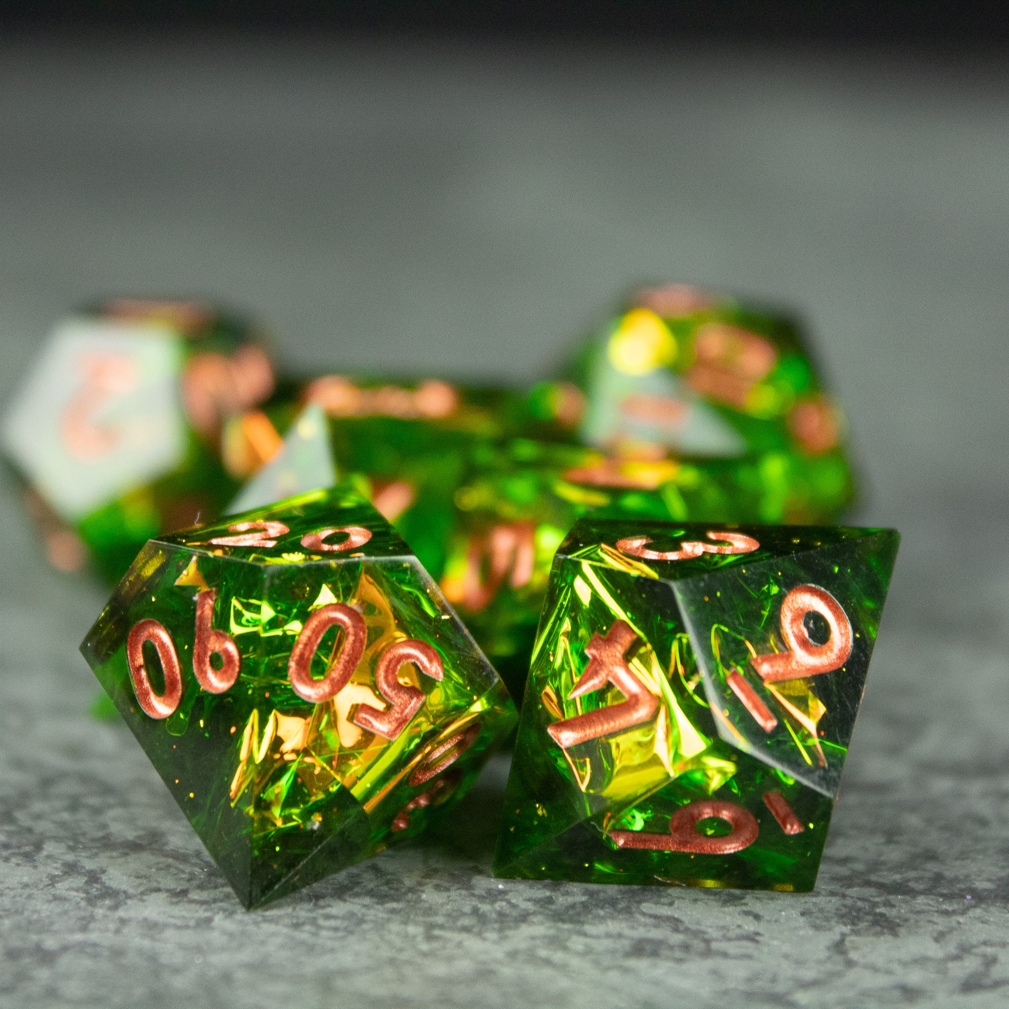 Venom Dice Set - Set of green, sharp-edged polyhedral dice with copper-colored numbers and a translucent, glossy finish.