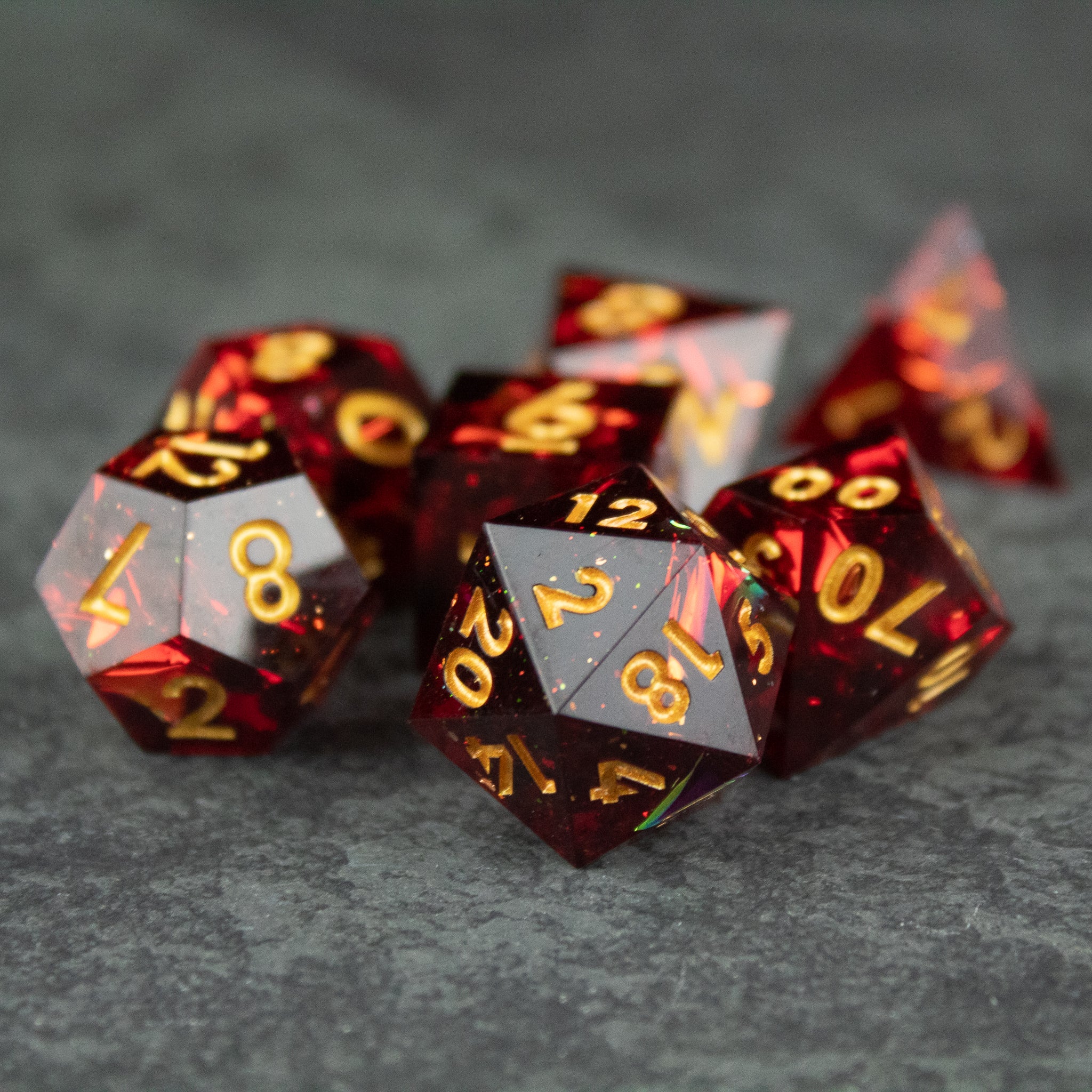 Ember Dice Set - Set of translucent red polyhedral dice with sharp edges and golden numbers, including d20 and d12.