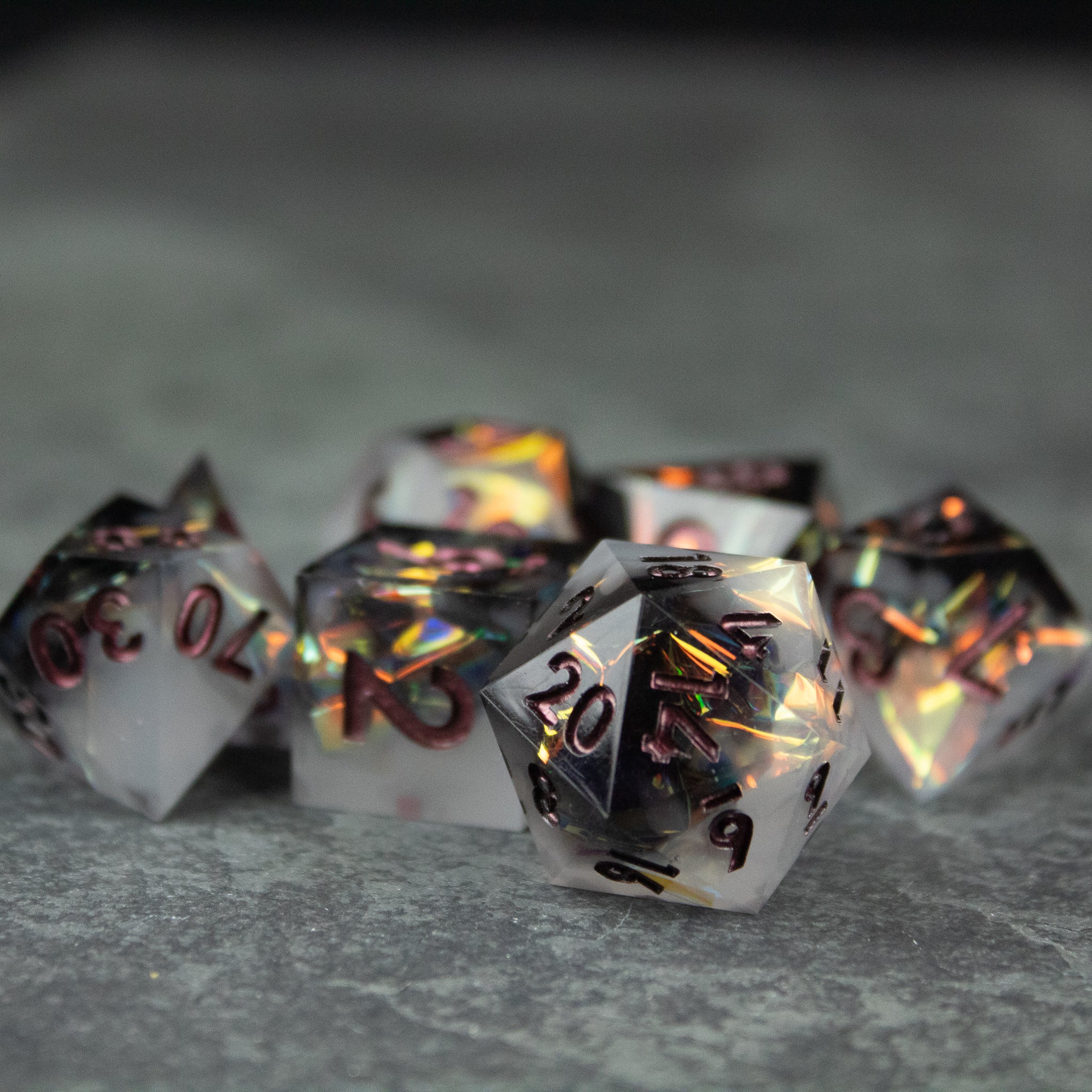 Oathbreaker Dice Set - Set of black and white sharp-edged dice with metallic gold and red numbering on a gray surface.