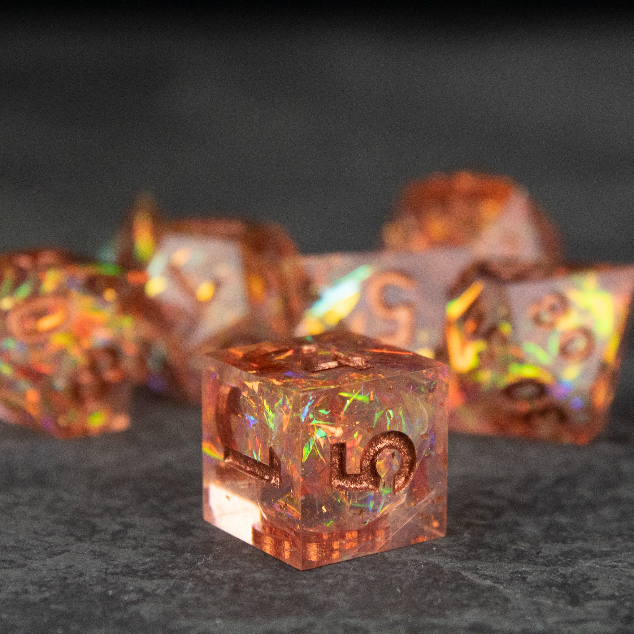 Sacred Flame Dice Set - Transparent orange sharp-edged dice set with fiery internal sparkles and gold numbers.