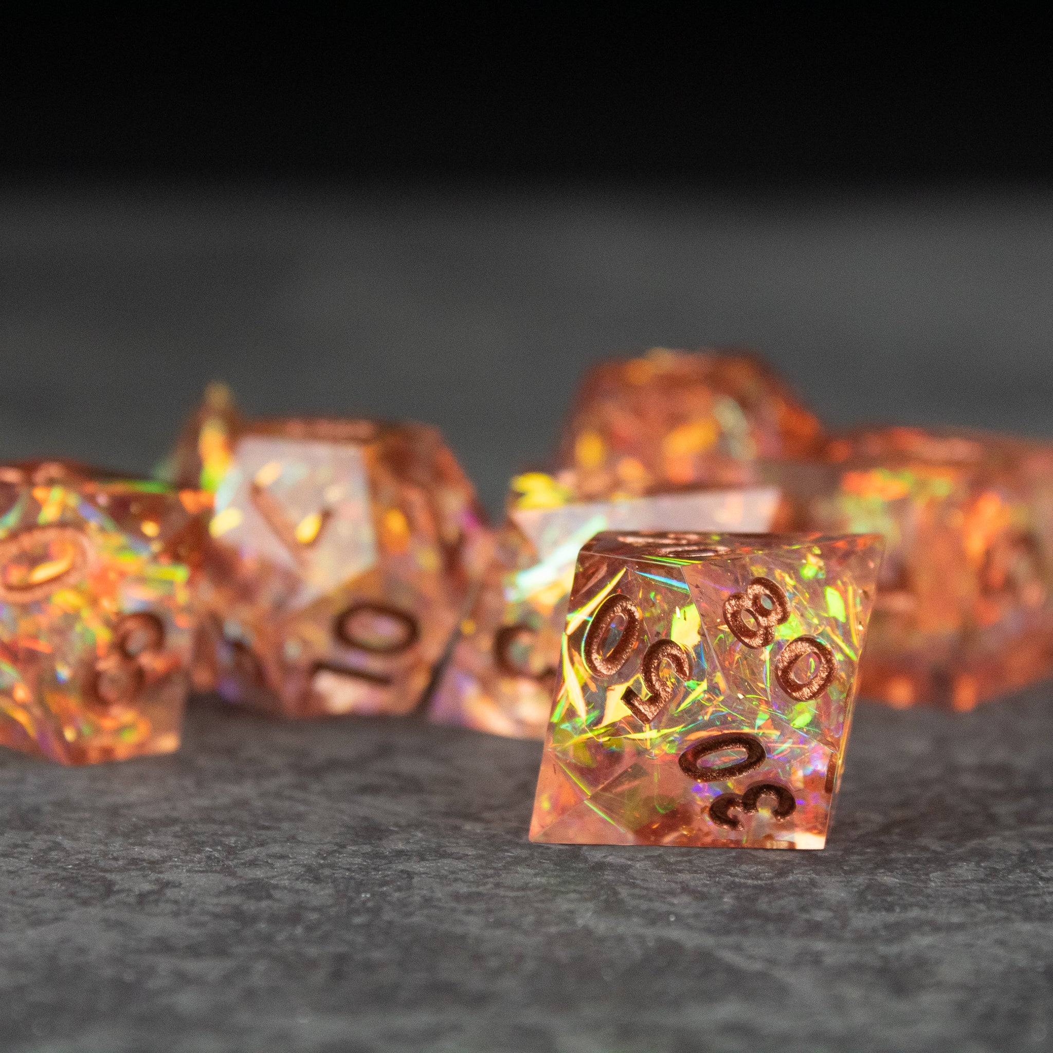 Sacred Flame Dice Set - Translucent orange polyhedral dice with sharp edges and fiery gold flecks, etched black numbers.