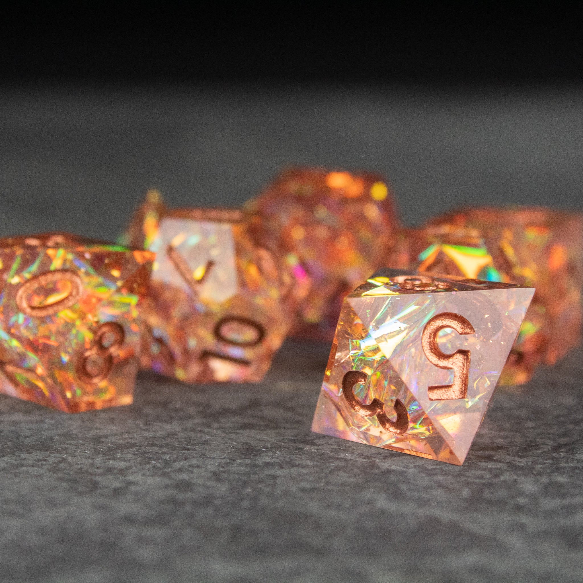 Sacred Flame Dice Set - Translucent orange polyhedral dice set with sharp edges and glittering inclusions, numbers in copper-tone.
