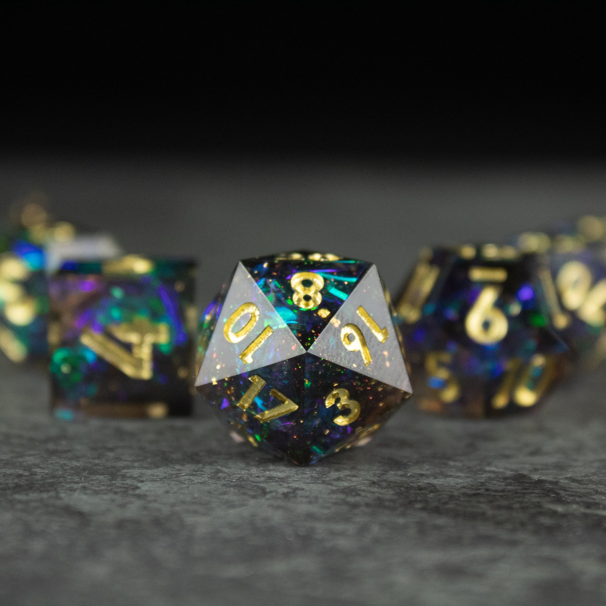 Galaxy Dice Set - Black sharp-edged d20 dice with gold numbers and galaxy speckled design on dark surface.