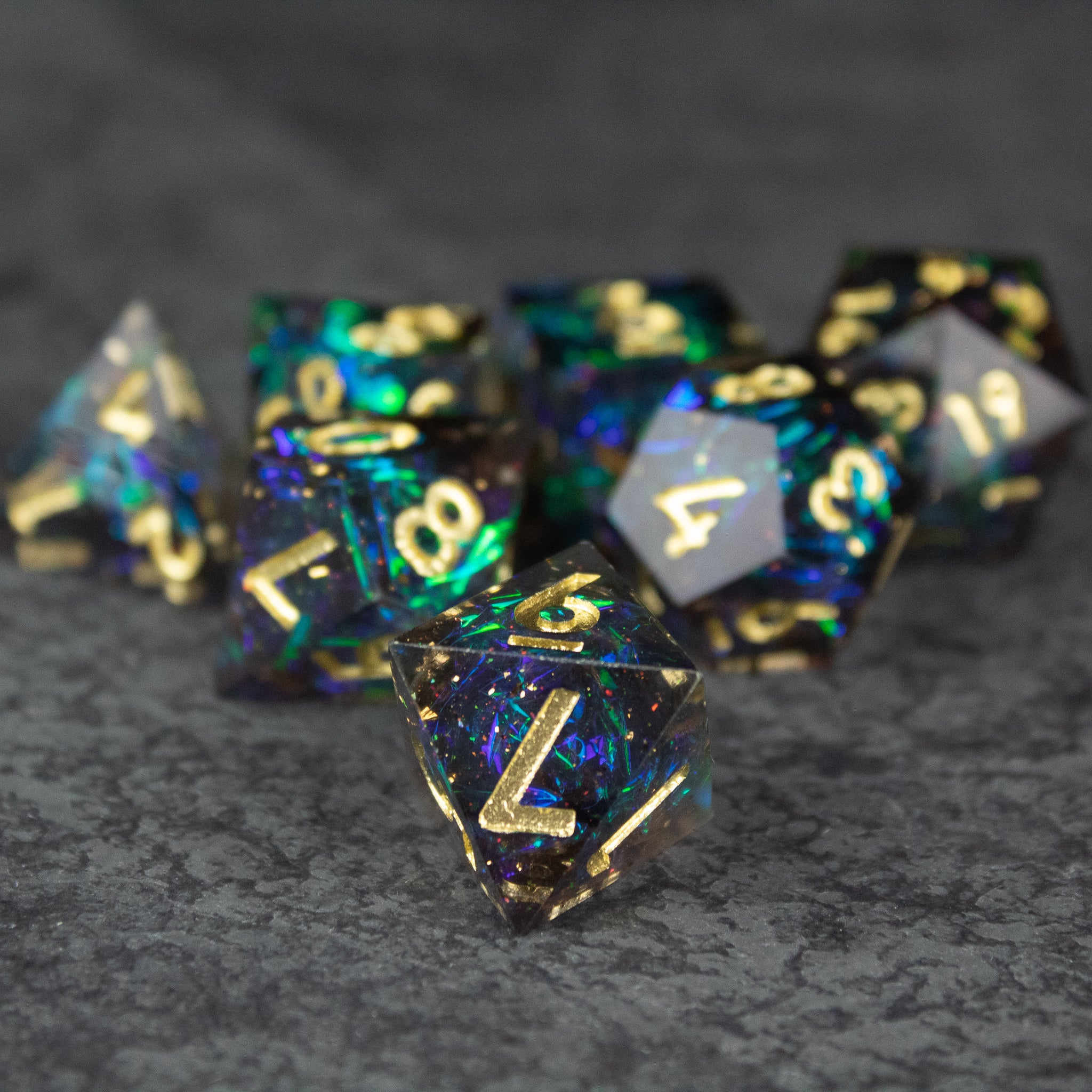 Galaxy Dice Set - Set of sharp-edged black and translucent dice with gold numbers and galaxy-inspired blue and purple glitter inside.
