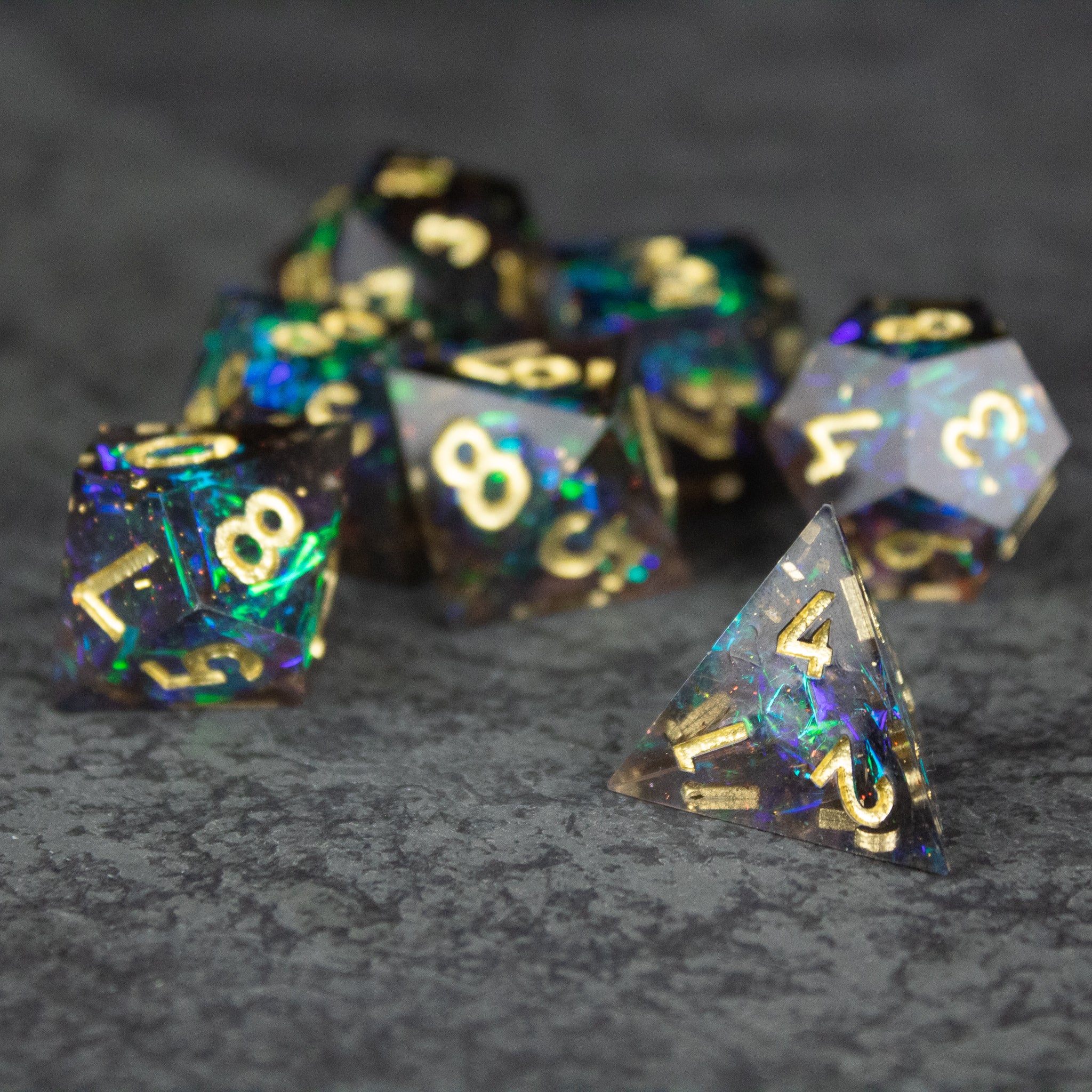 Galaxy Dice Set - Set of black sharp-edged polyhedral dice with blue, purple, and gold swirls and gold numbering.