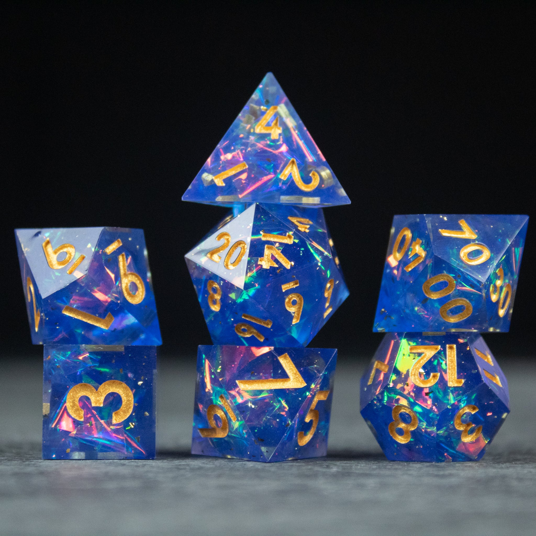 Arcana Dice Set - Blue resin dice set with sharp edges and gold numbers, featuring swirling patterns inside.