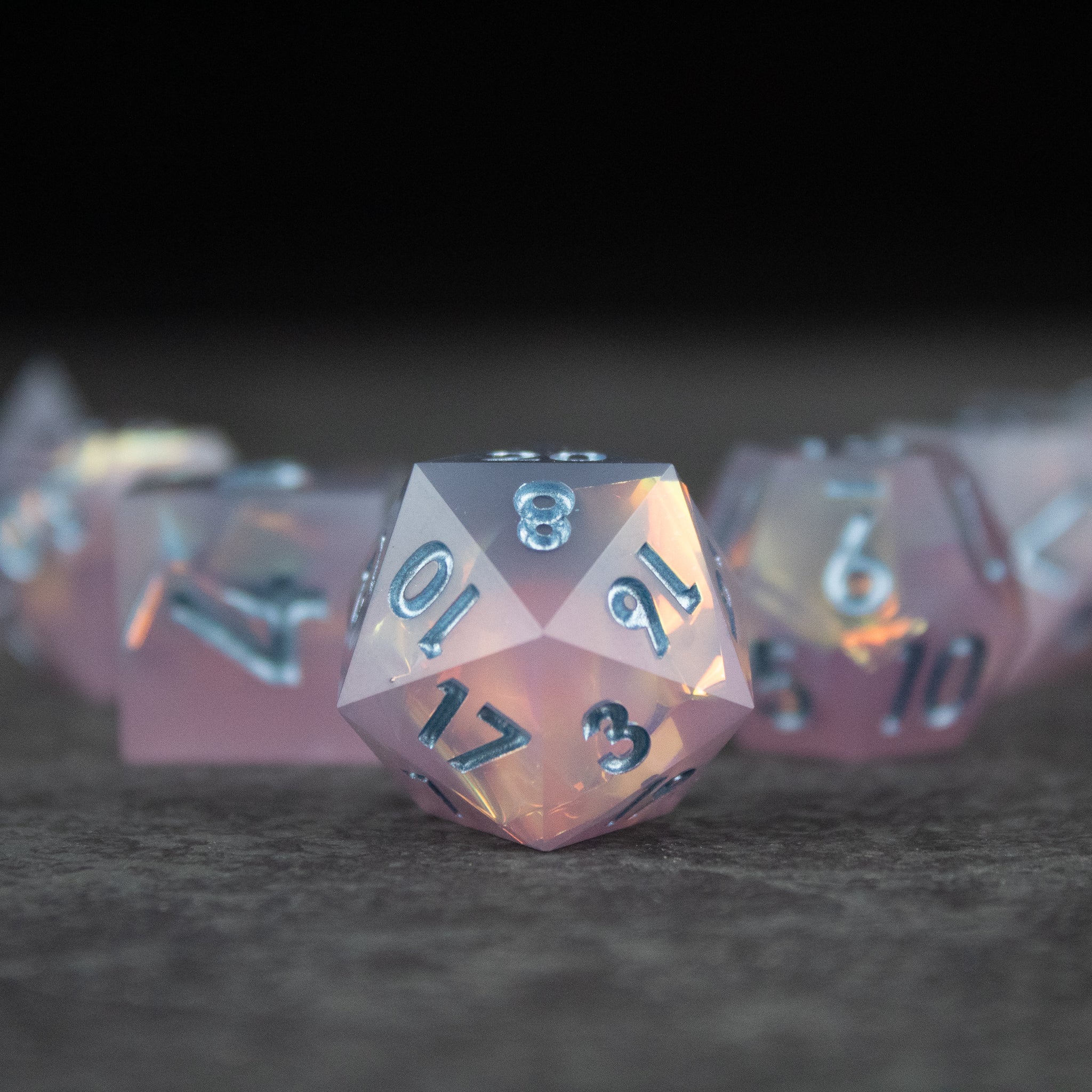 Moonshard Dice Set - Translucent pink sharp-edged 20-sided dice with silver numbers and glossy finish.