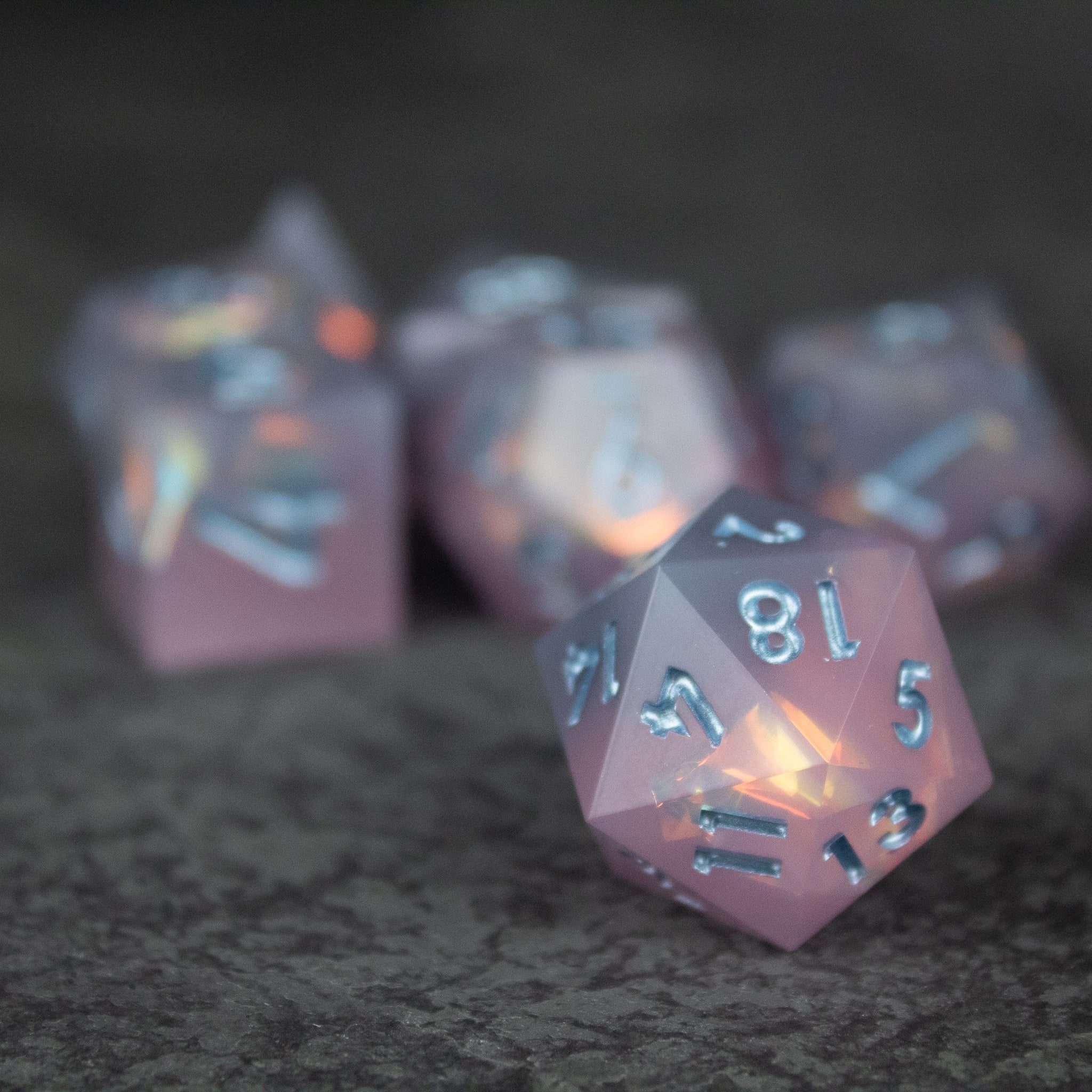 Moonshard Dice Set - Translucent pink 20-sided dice with sharp edges and silver numbering, glowing softly from within.