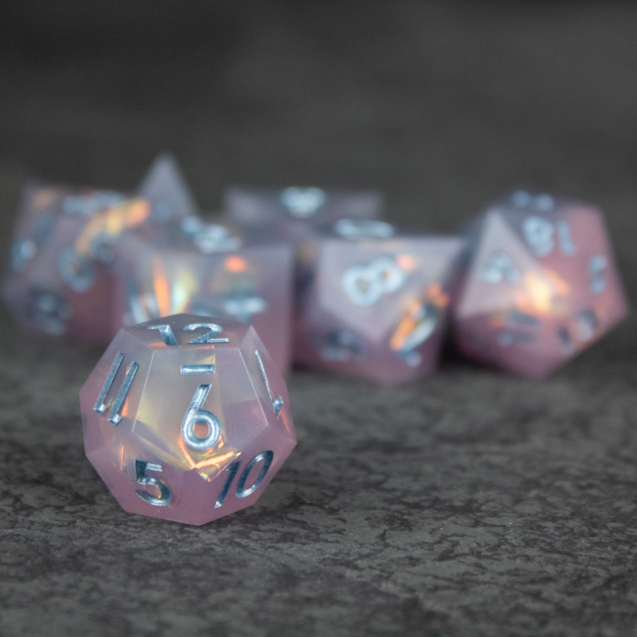 Moonshard Dice Set - Set of translucent pink sharp-edged polyhedral dice with metallic silver numbers.
