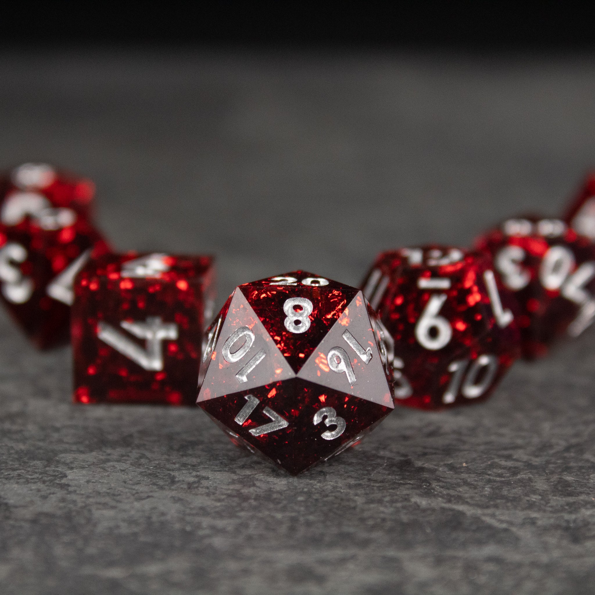 Inferno Dice Set - Red translucent sharp-edged polyhedral dice with white numbering, front die showing number eight on gray face.