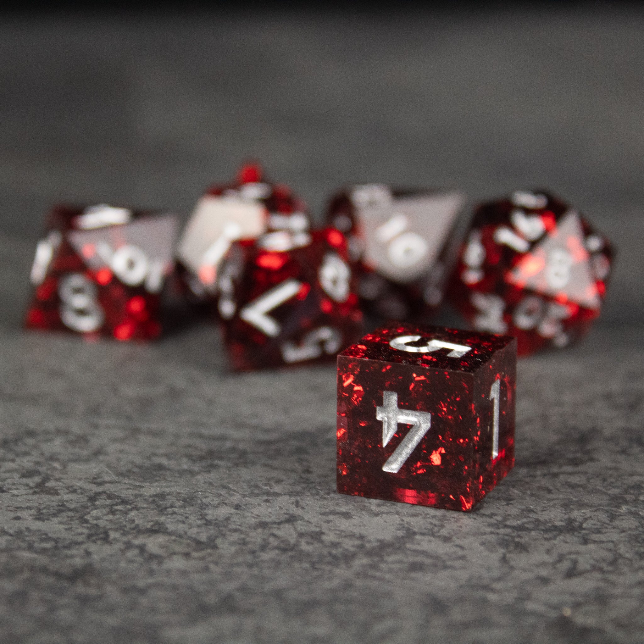 Inferno Dice Set - Red translucent sharp-edged polyhedral dice set with white numbers on a gray surface.
