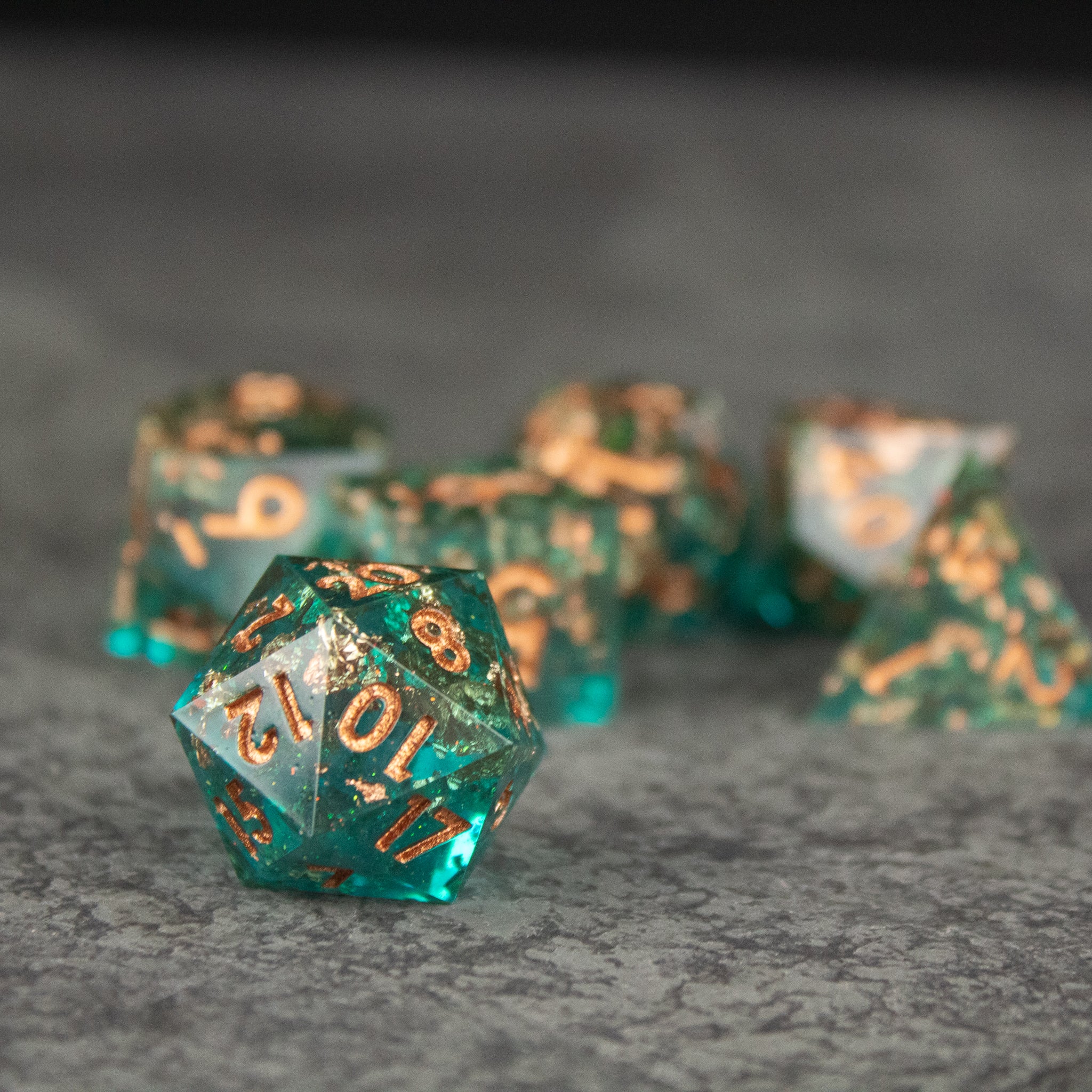 Oasis Dice Set - Translucent green 20-sided dice with sharp edges and gold numbering, set on a textured surface.
