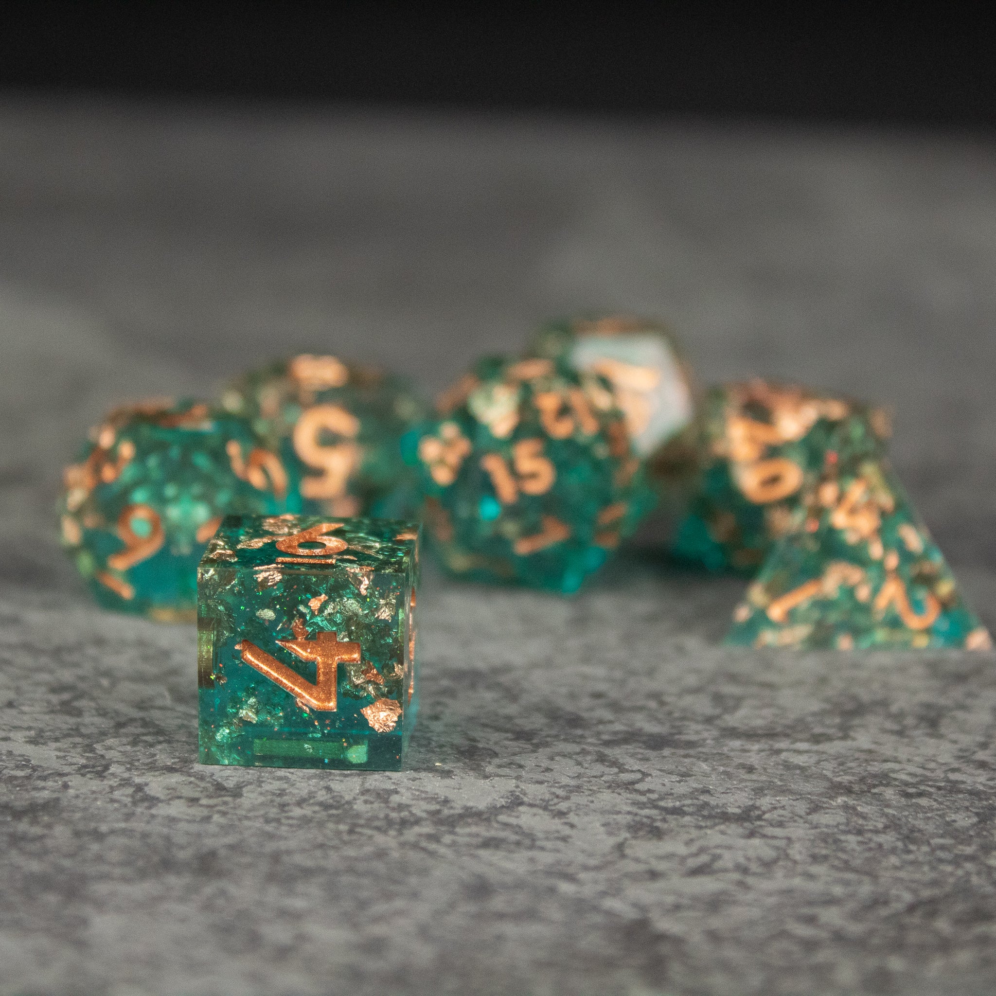 Oasis Dice Set - Translucent green sharp-edged dice set with gold numbers on gray surface.