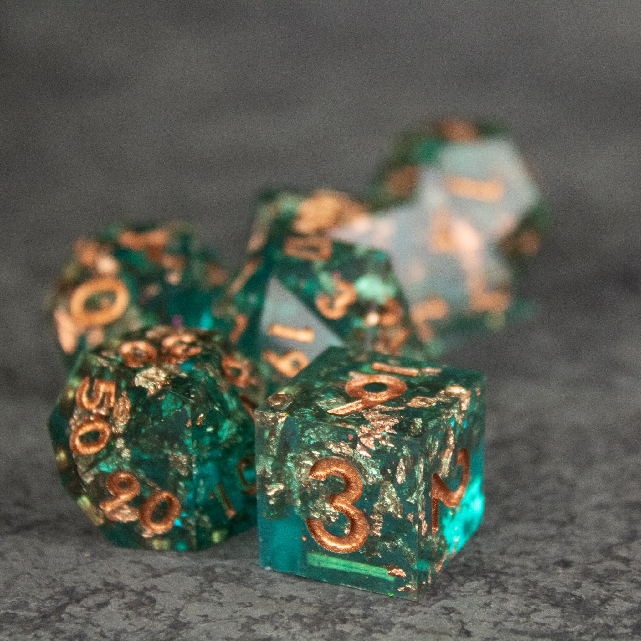 Oasis Dice Set - Translucent green gemstone dice with sharp edges and copper-colored numbers, set of polyhedral shapes.