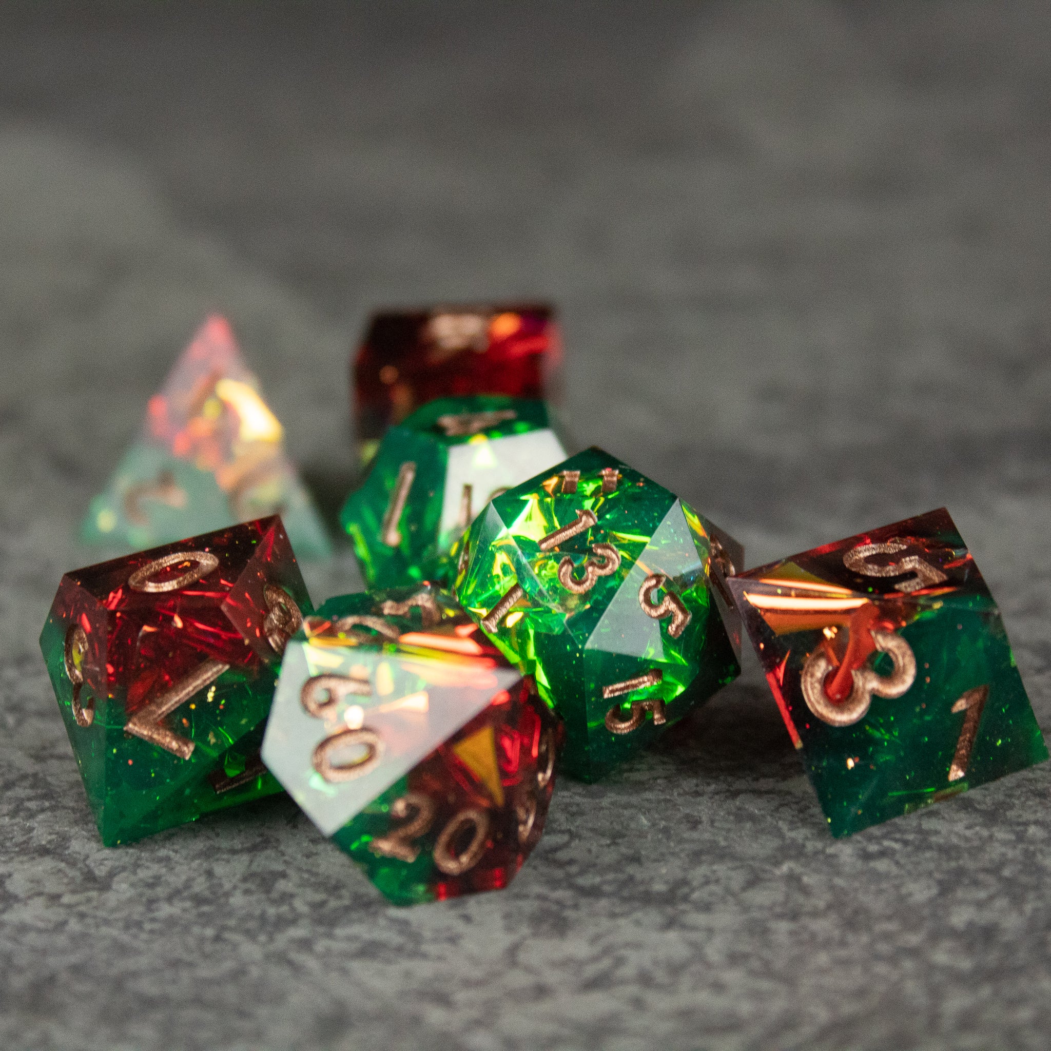 Jungle Fire Dice Set - Set of polyhedral dice with sharp edges, featuring green and red translucent halves and gold numbering.
