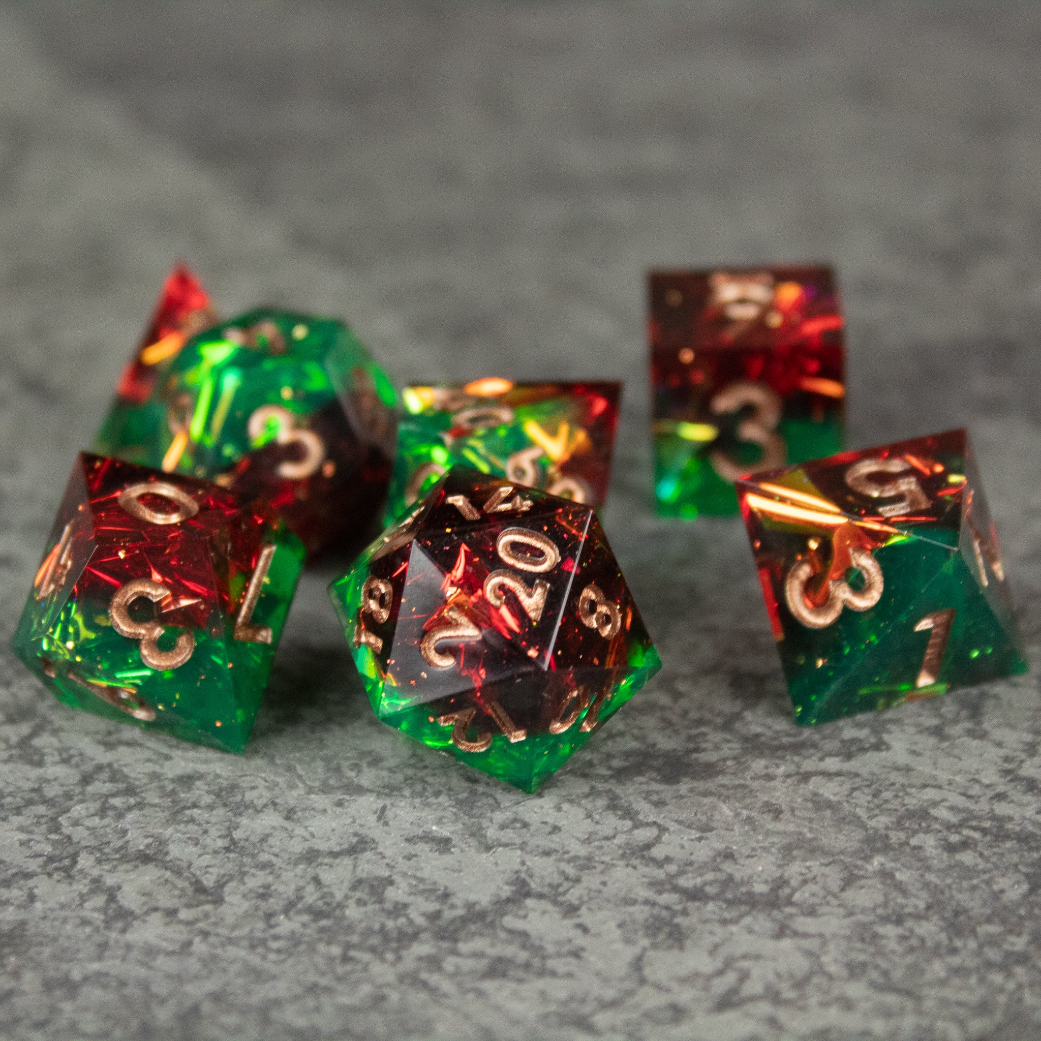 Jungle Fire Dice Set - Set of seven translucent polyhedral dice in green and red with sharp edges and gold numbering.