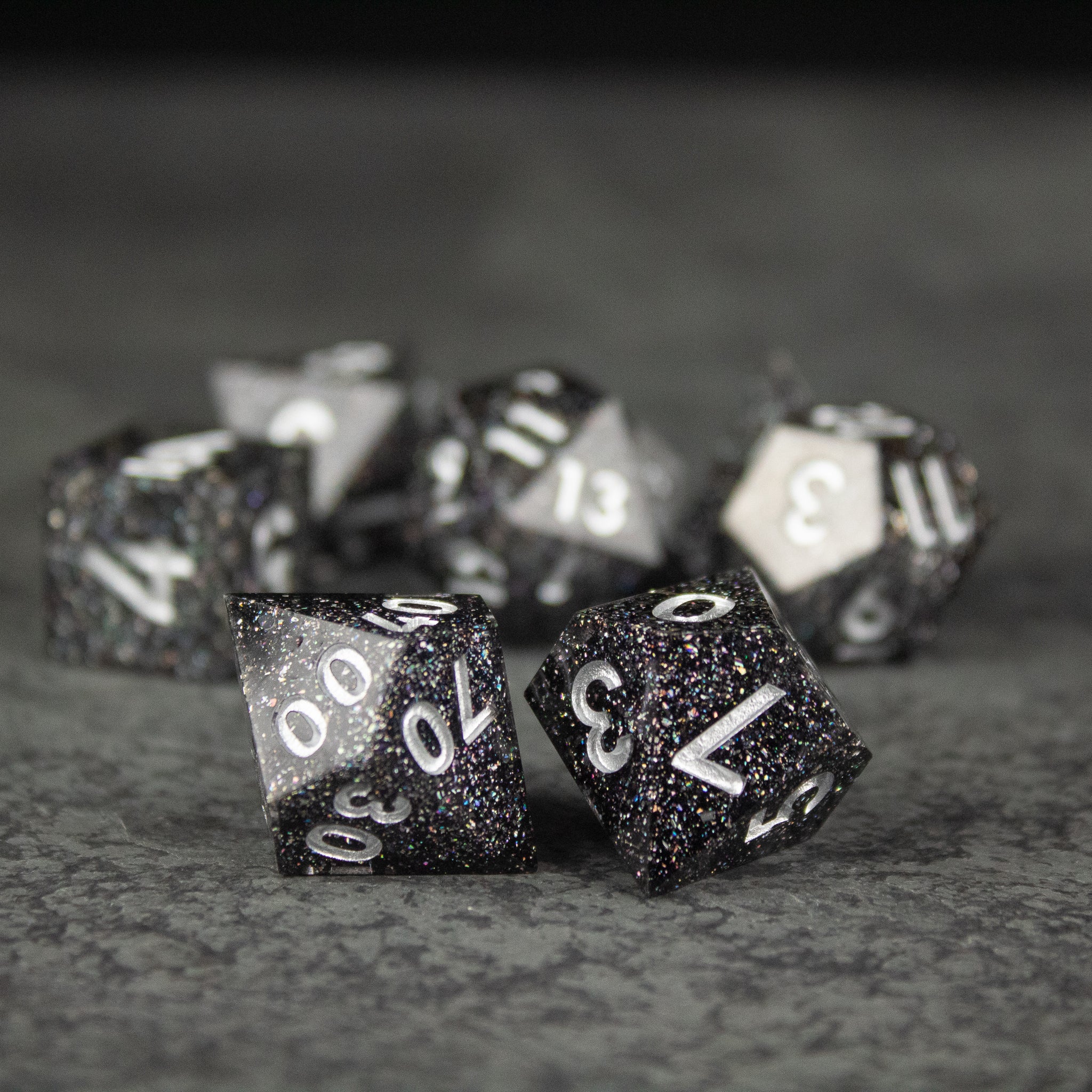 Starfield Dice Set - Black glittery polyhedral dice set with white numbers, sharp edges, and varied shapes.
