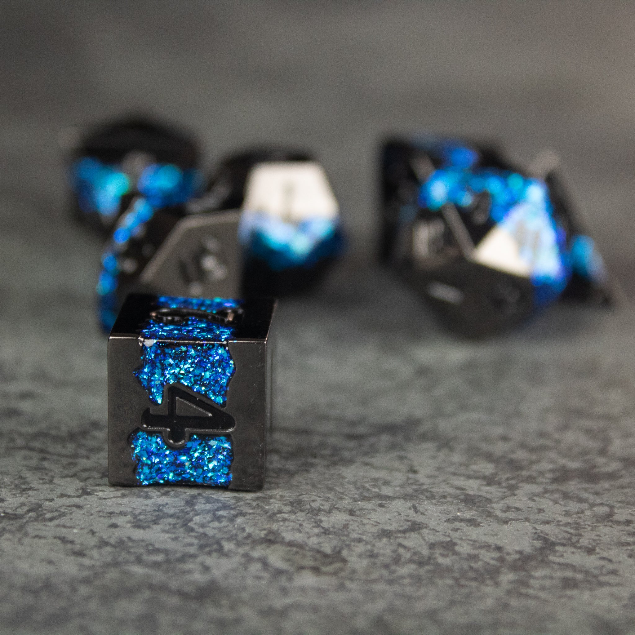 Blue Rift Dice Set - Black metal dice with bright blue glitter accents, sharp edges, and engraved numbers.