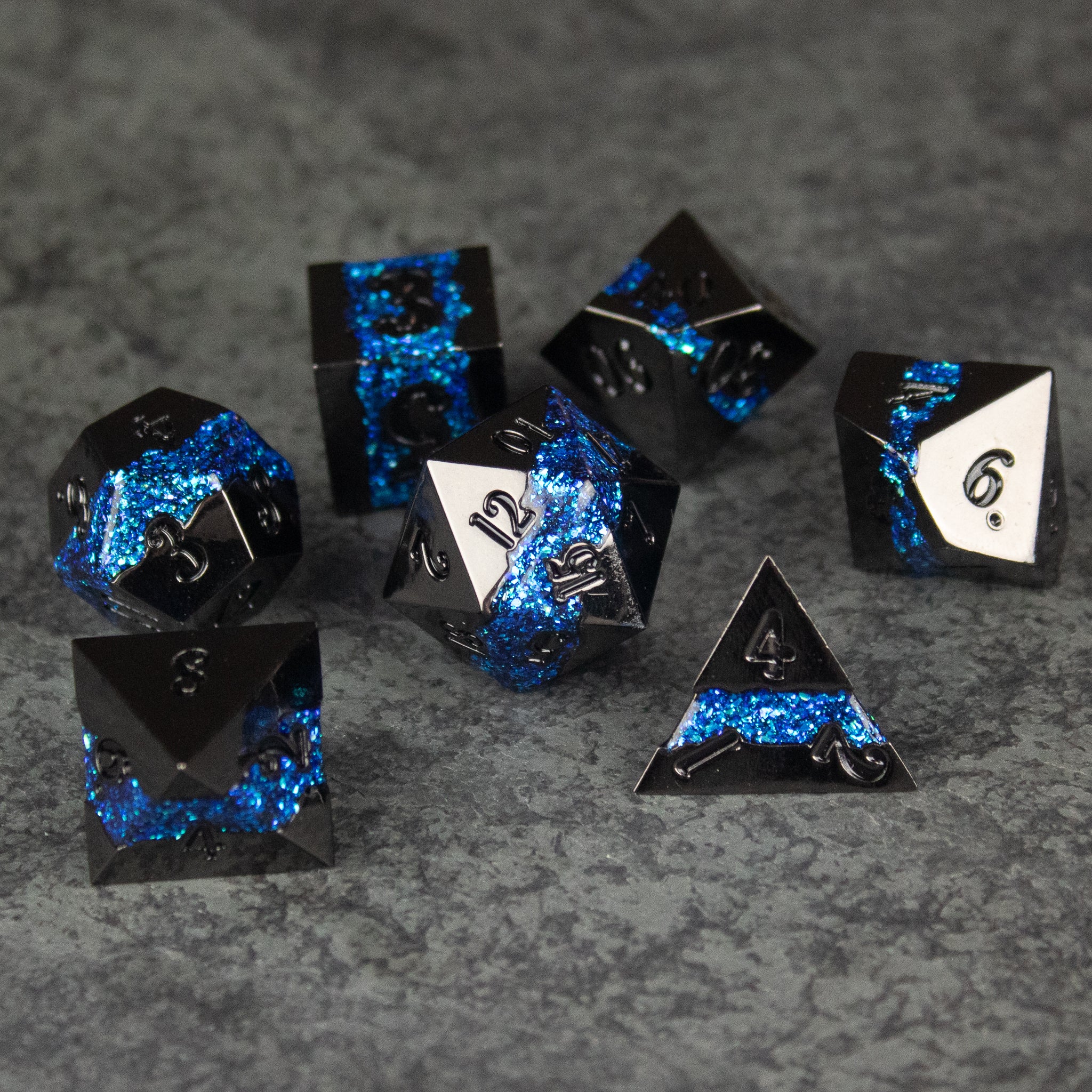 Blue Rift Dice Set - Set of seven black metal polyhedral dice with bright blue crackle pattern and white numbering.