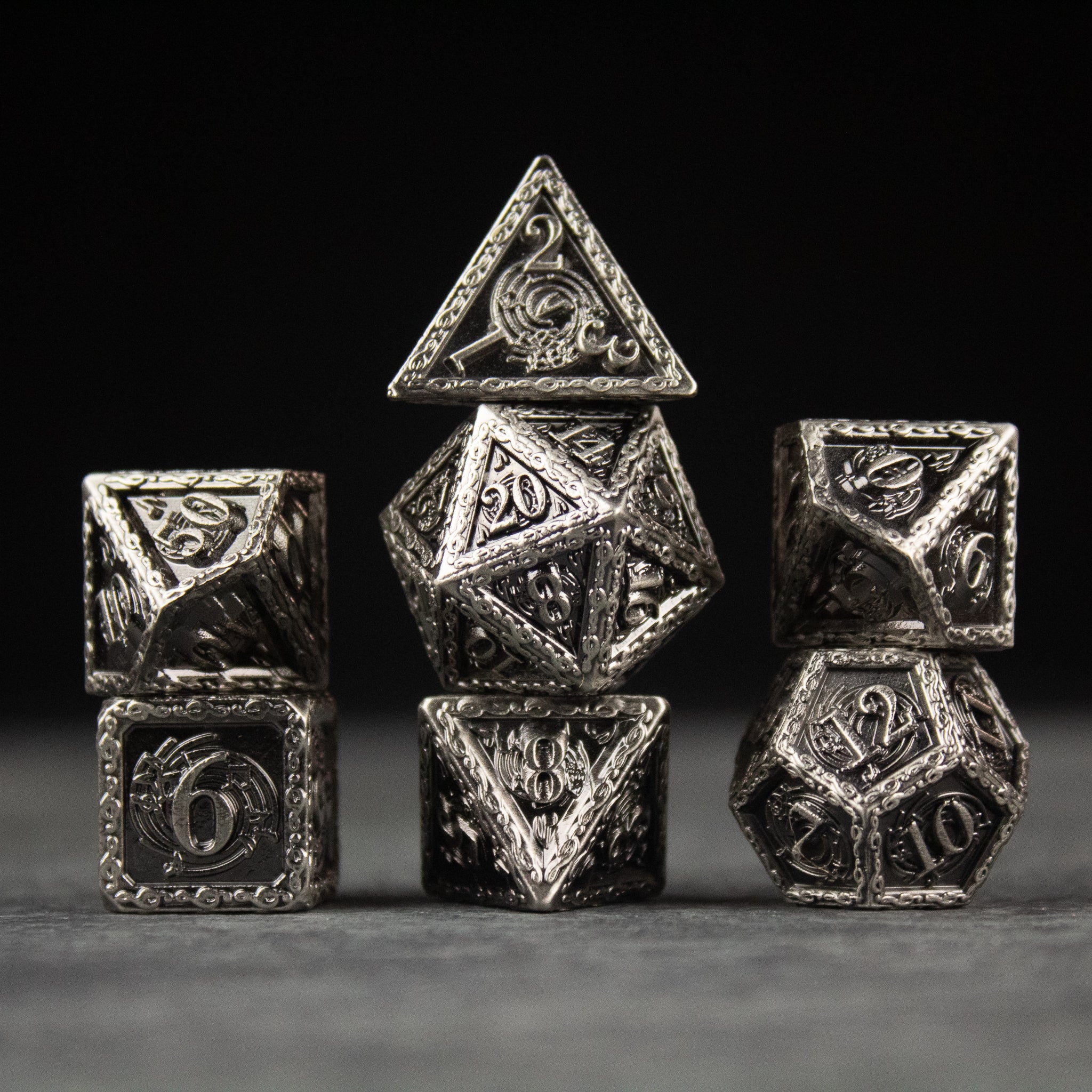 Bardic Inspiration Metal Dice Set - Set of seven silver metal polyhedral dice with intricate bardic and musical engravings.