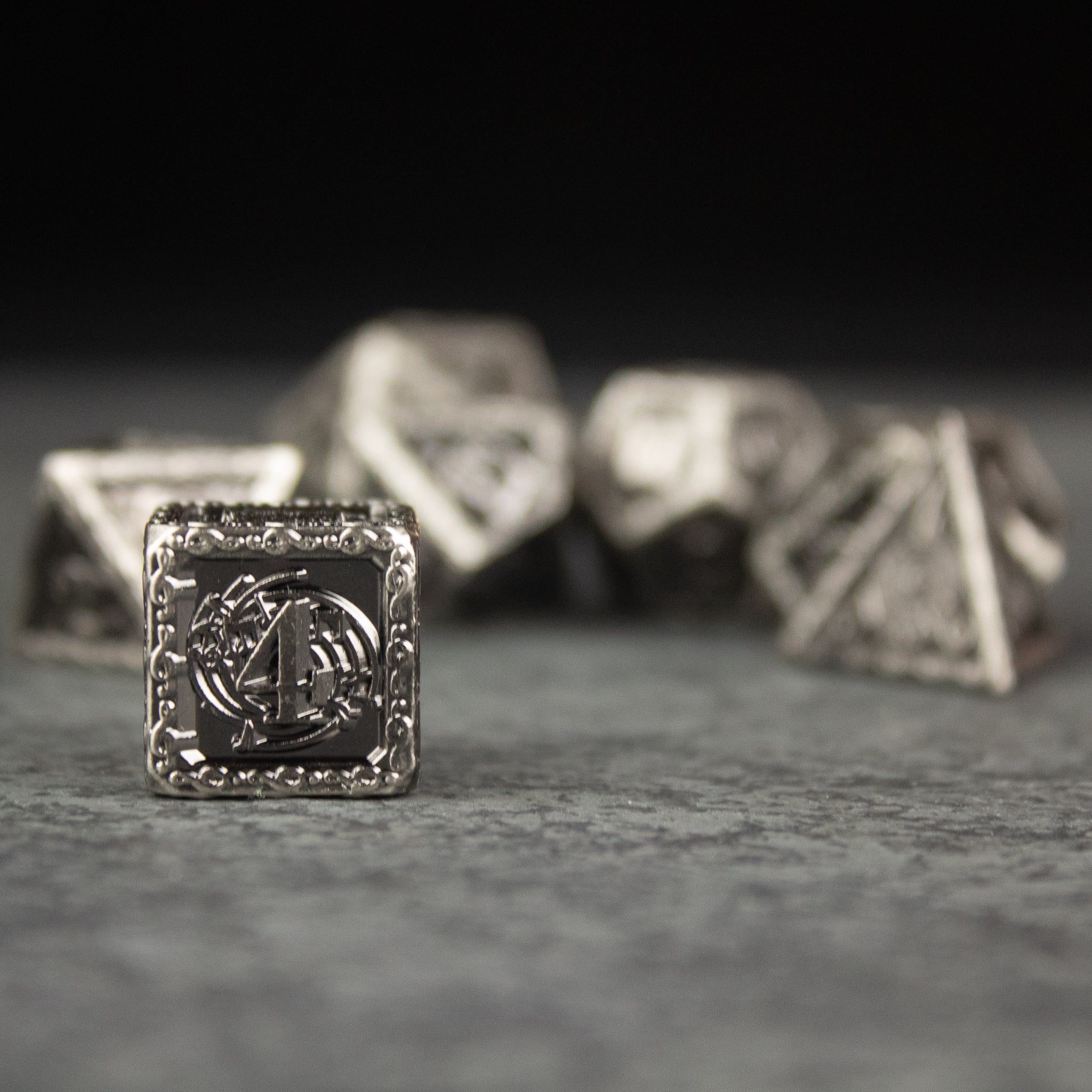 Bardic Inspiration Metal Dice Set - Silver metal dice set with textured edges and an engraved harp design on the d4 face.