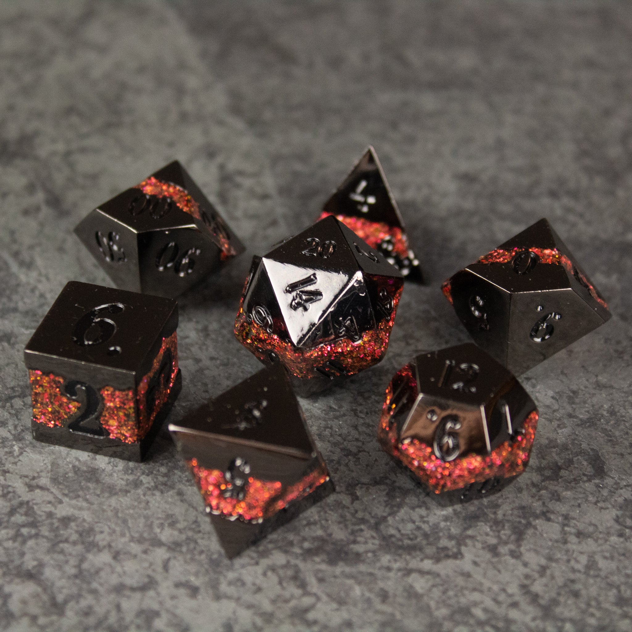 Red Rift Metal Dice Set - Seven black metal polyhedral dice with red crackle details, including d20, d12, d10, d8, d6, and d4 types on a gray textured .