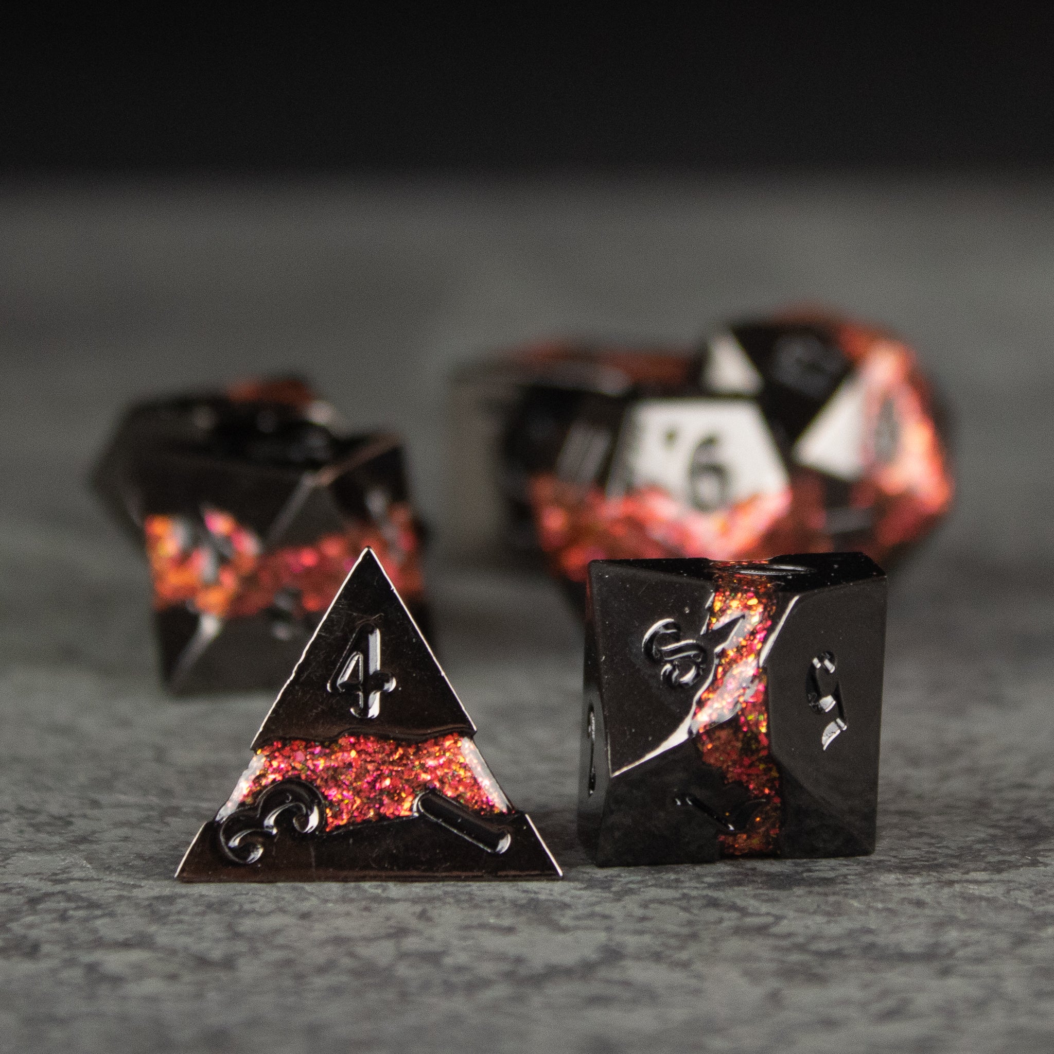 Red Rift Metal Dice Set - Red and black marbled metal dice set with sharp edges and engraved white numbers, including a four-sided and six-sided die.