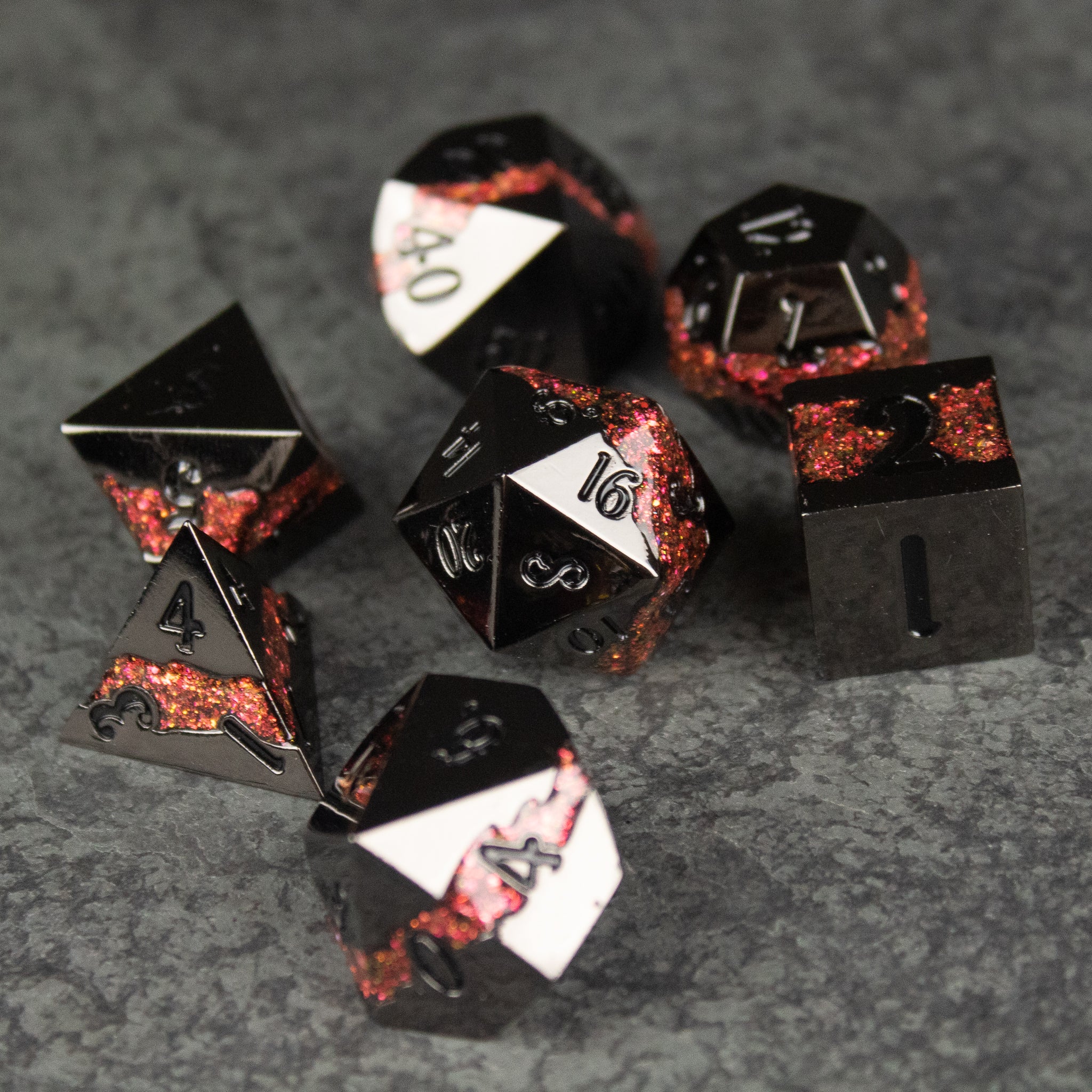 Red Rift Metal Dice Set - Red and black metal polyhedral dice set with sharp edges and white numbering on a textured gray surface.