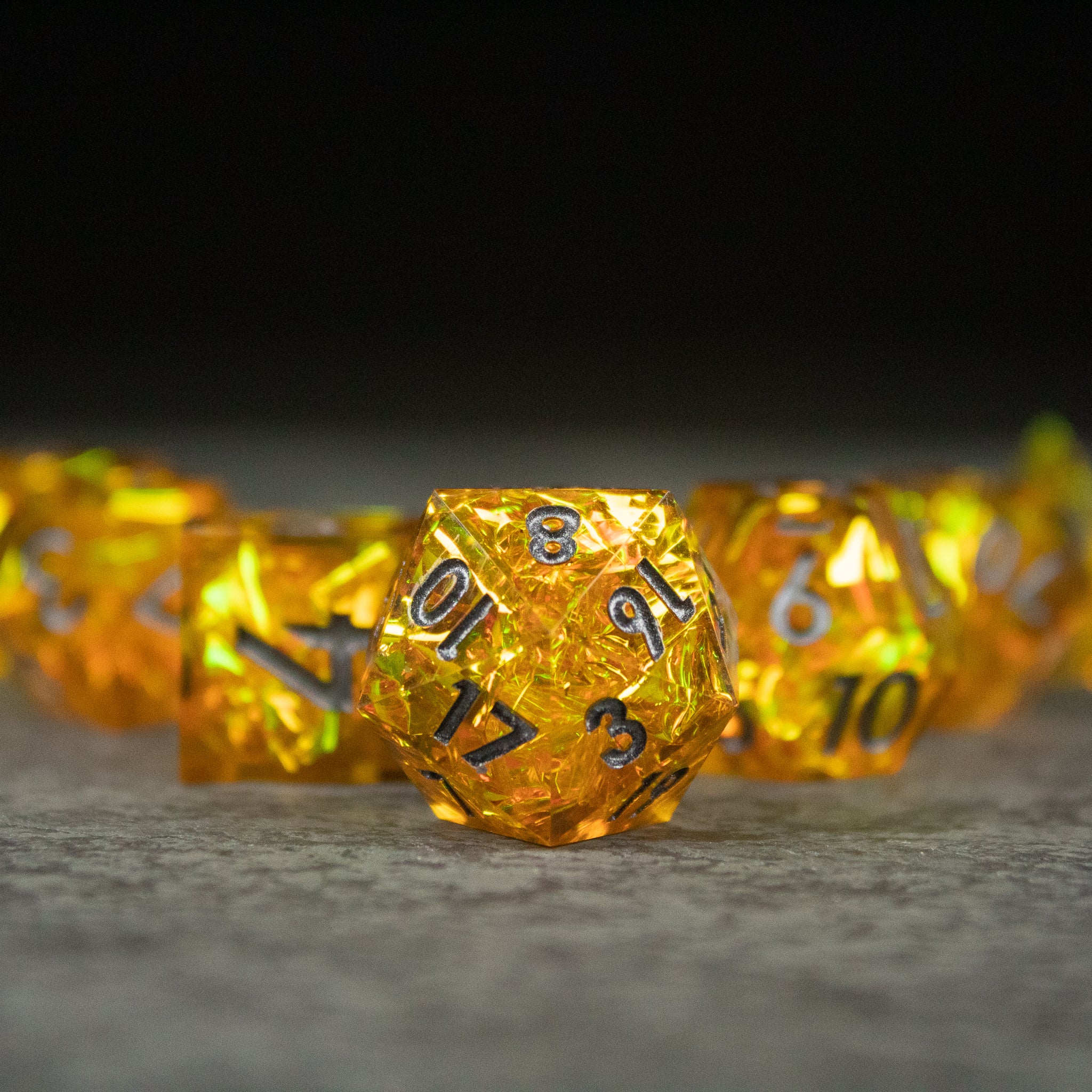 Golden Order Dice Set - Gold sharp-edged 20-sided die with black numbering among similar yellow dice on gray surface.
