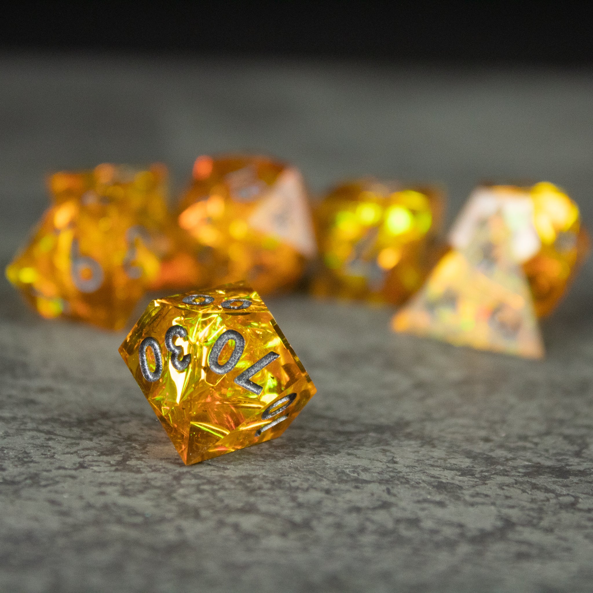 Golden Order Dice Set - Set of translucent gold polyhedral dice with sharp edges and black numbering on a gray surface.