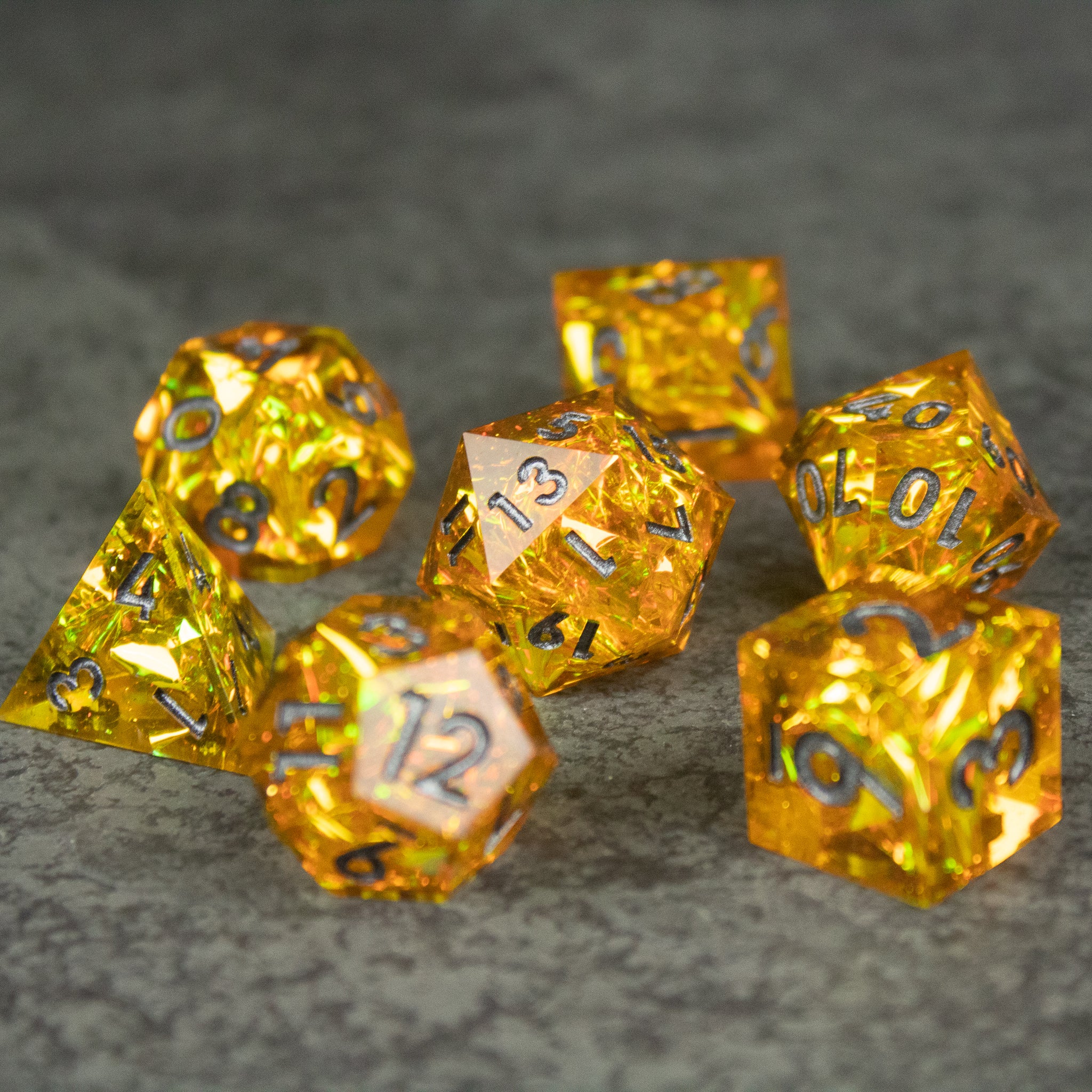 Golden Order Dice Set - Set of seven translucent amber-yellow polyhedral dice with sharp edges and black numbering on a gray textured surface.