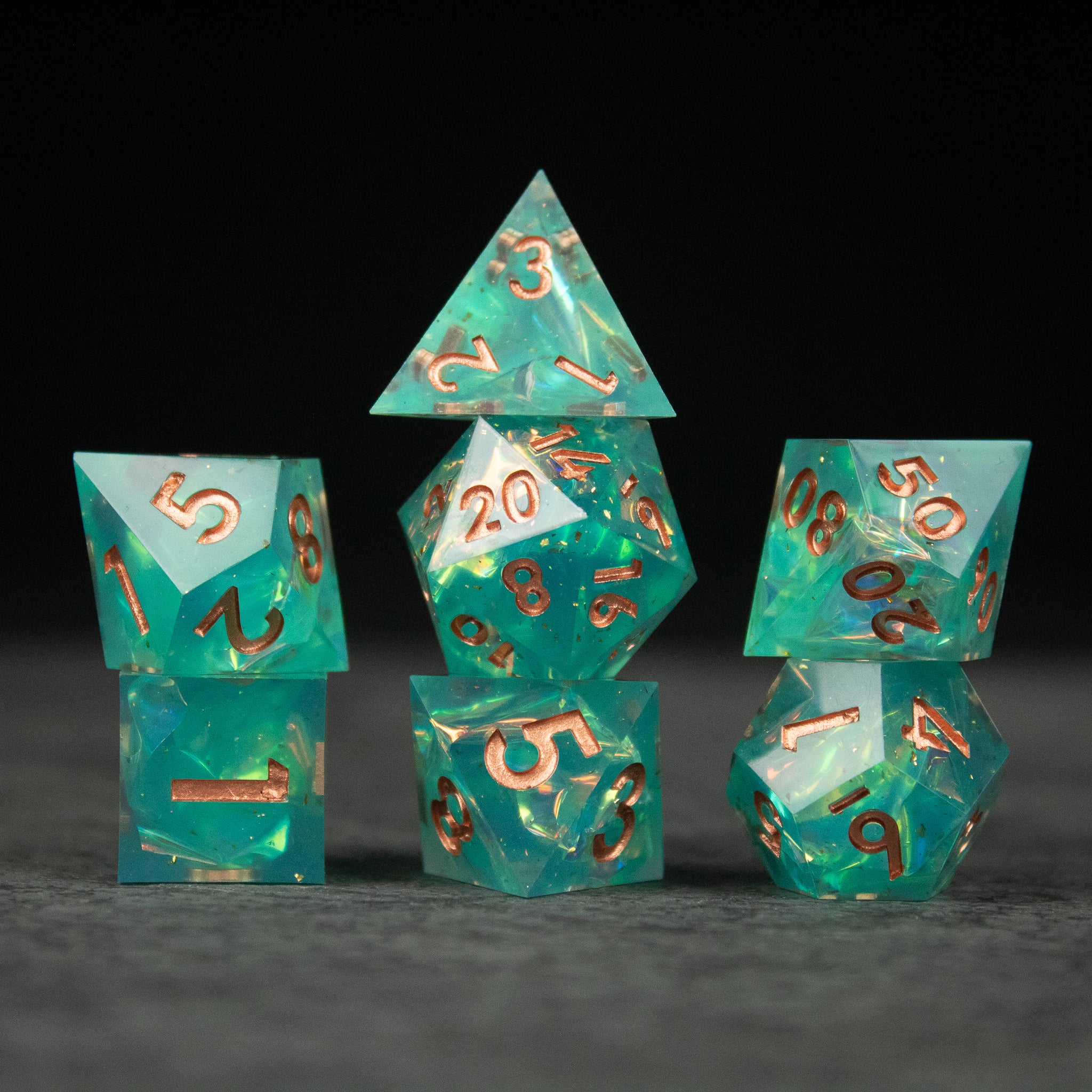 Residuum Dice Set - Set of seven aquamarine sharp-edged dice with copper-colored numbers on a dark background.