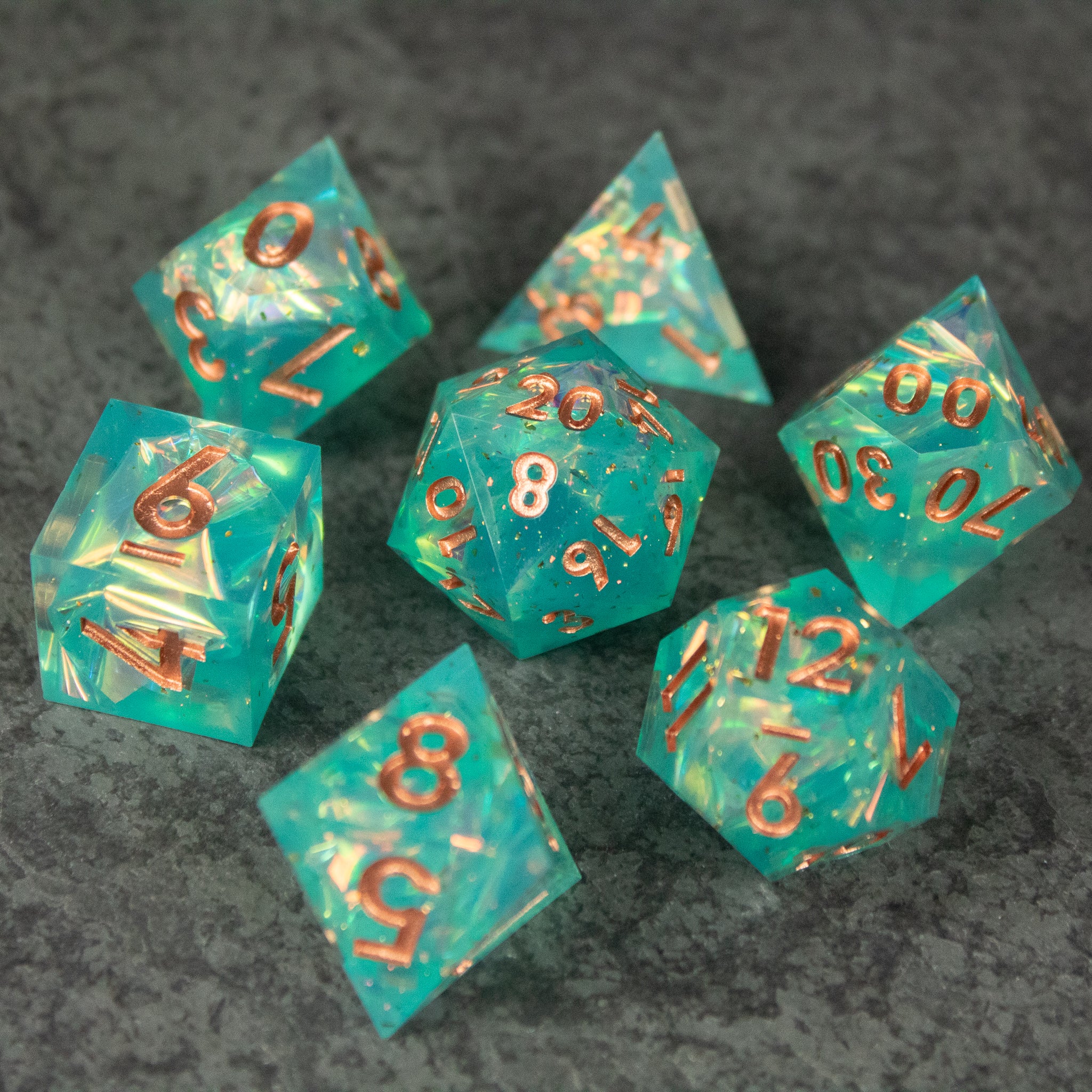 Residuum Dice Set - Seven sharp-edged translucent aquamarine dice with copper-colored numbers and gold flecks inside.