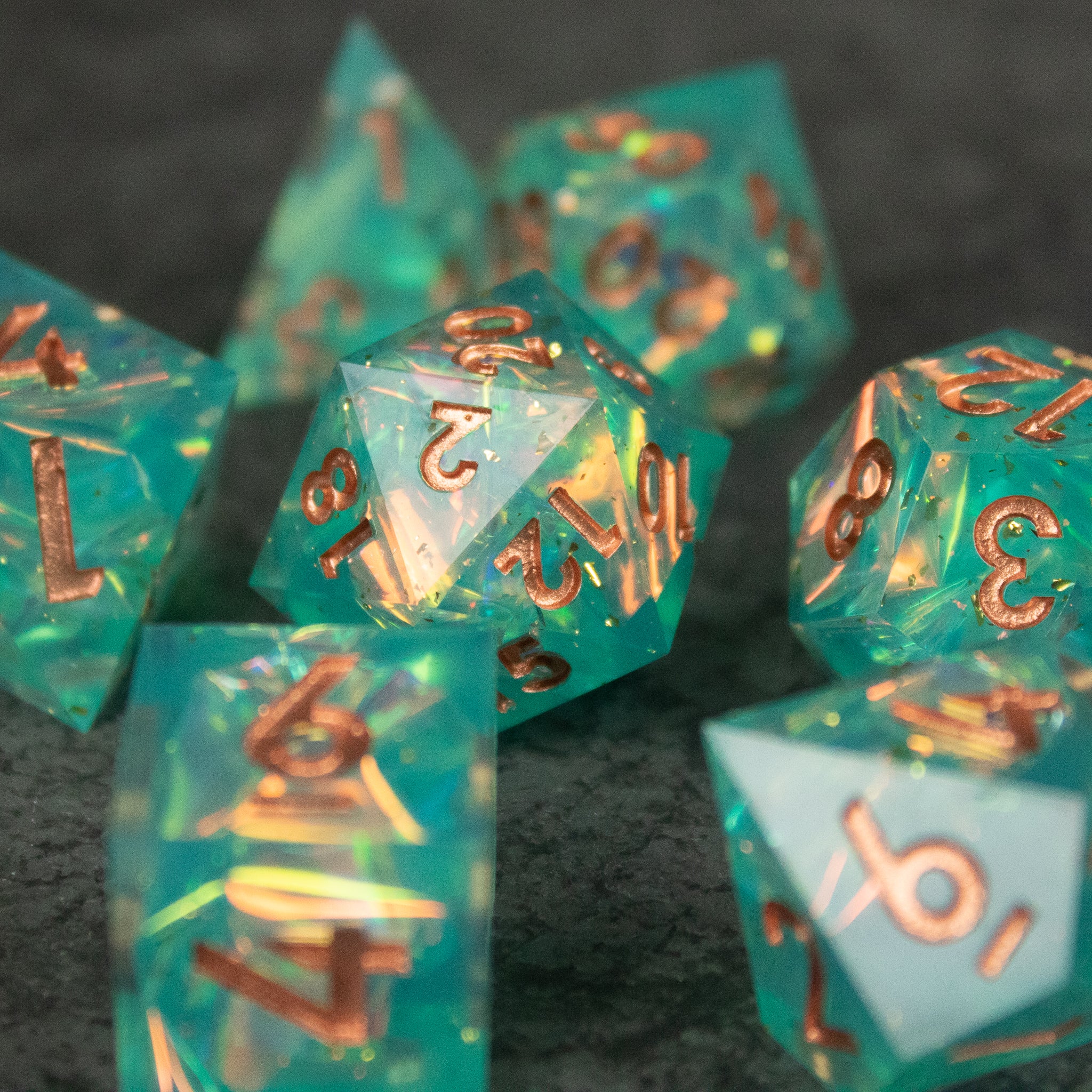Residuum Dice Set - Translucent aquamarine polyhedral dice set with sharp edges and metallic gold numbers.