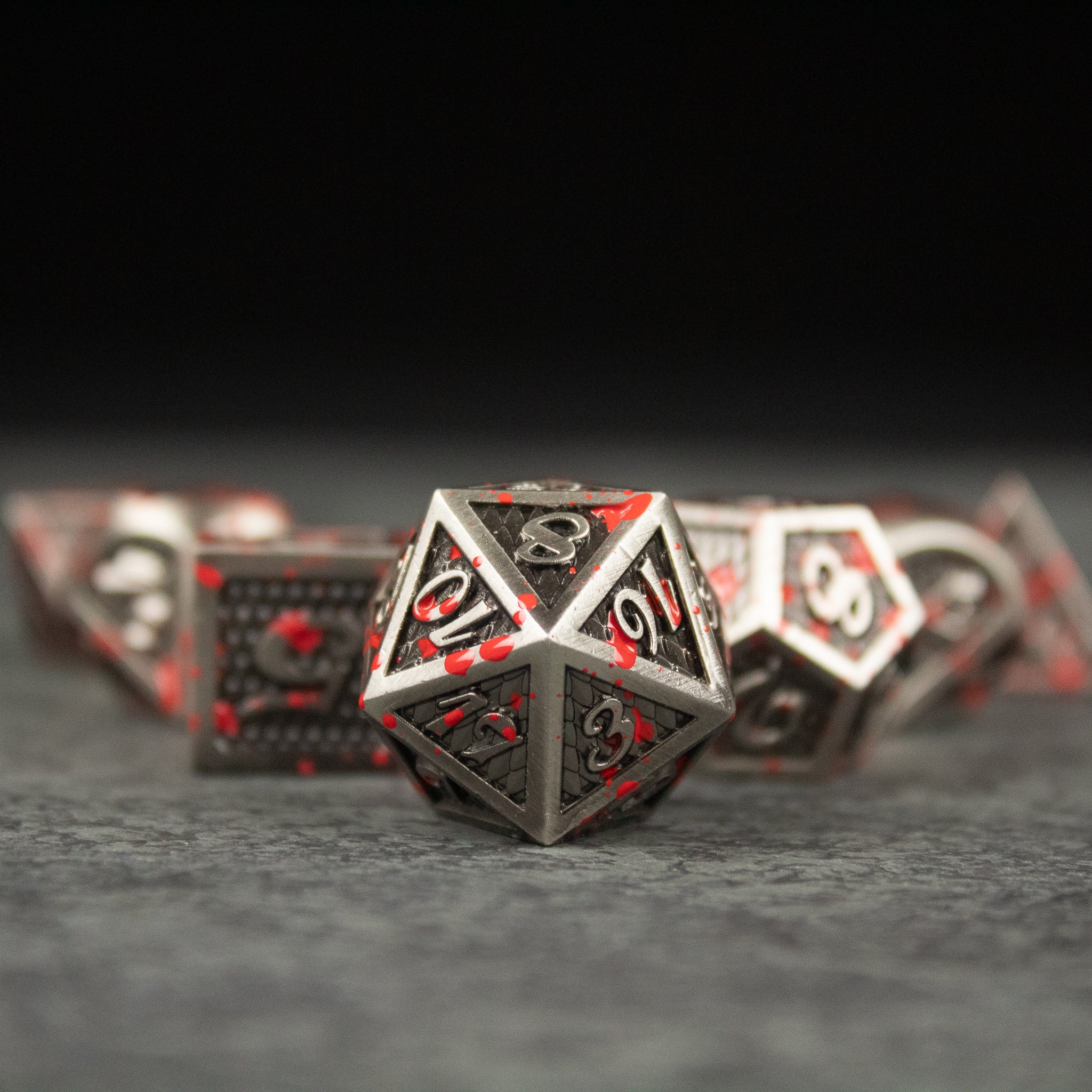 Marauder Dice Set - Metal Marauder dice set with dark finish and red numbering, featuring various polyhedral shapes including a d20.