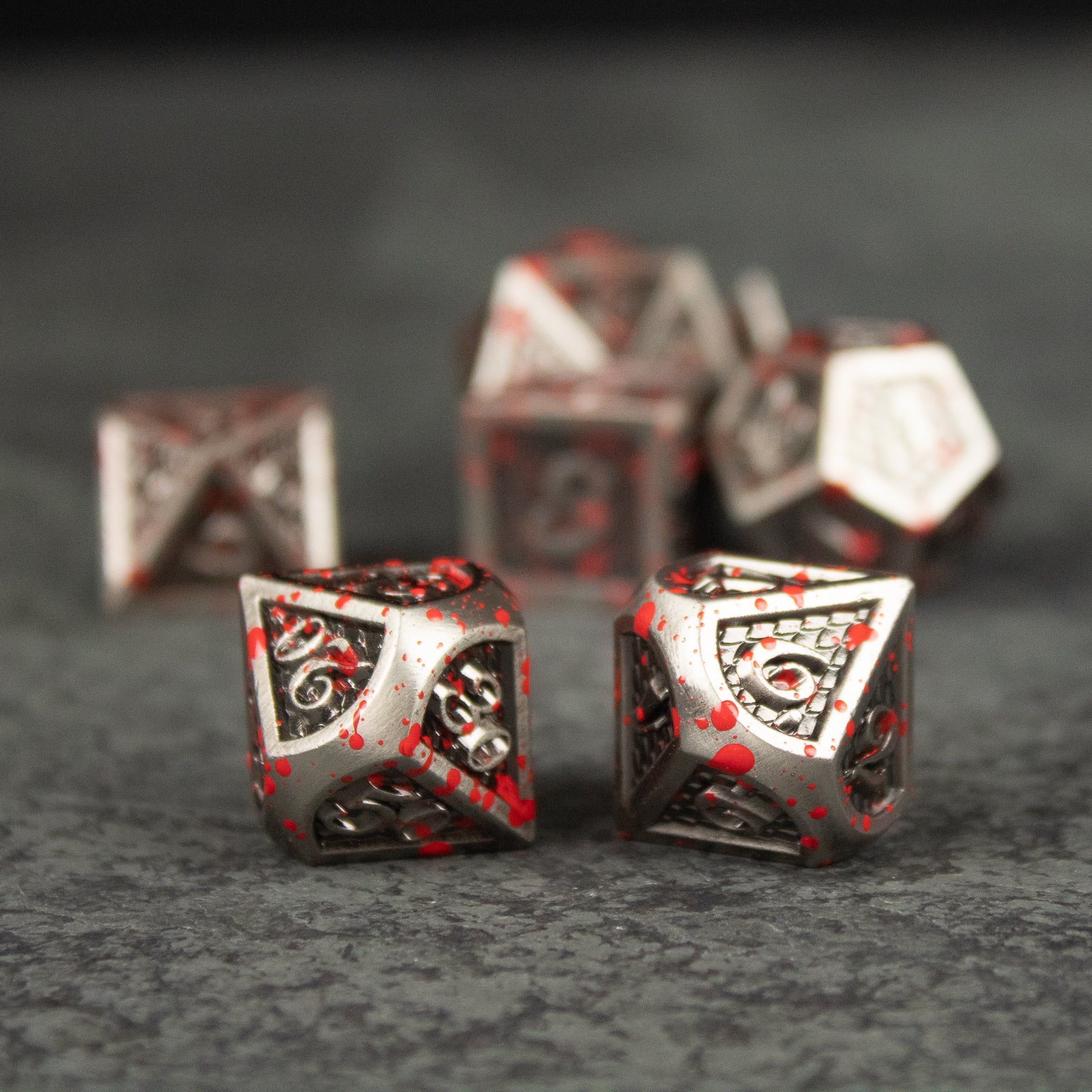 Marauder Dice Set - Metallic silver and black dice with red splatter accents, intricate engraved patterns, various polyhedral shapes.
