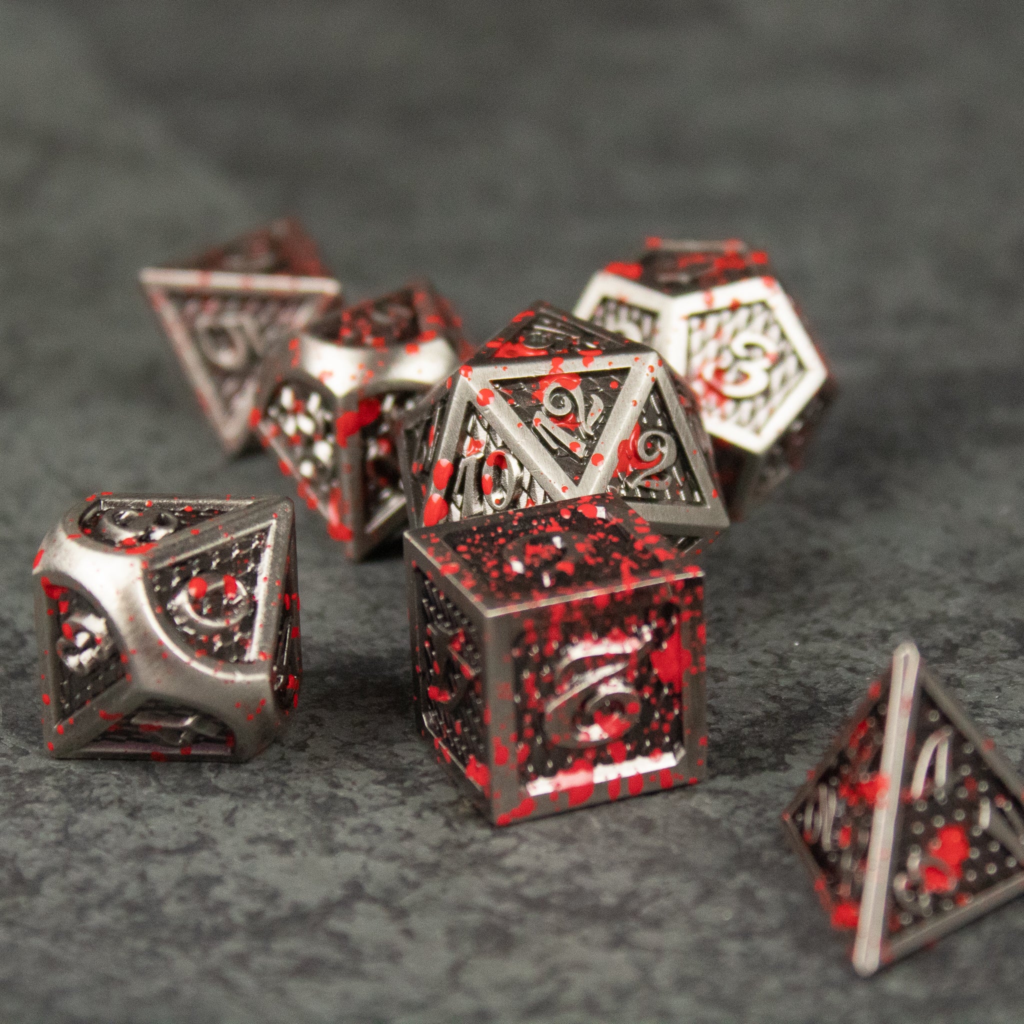Marauder Dice Set - Set of metal RPG dice with red and black marbled pattern including d20, d12, d10, d8, d6, and d4 shapes.