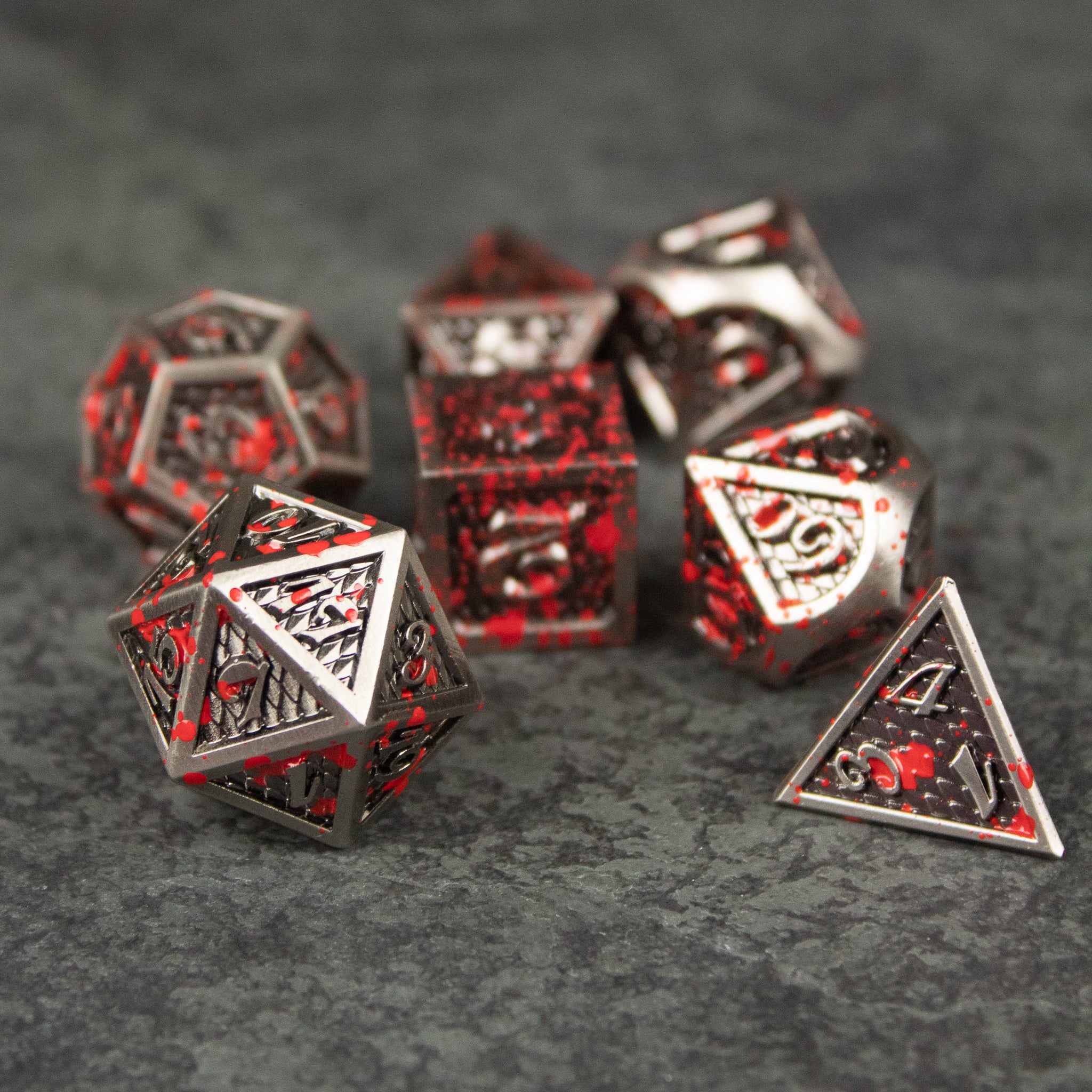 Marauder Dice Set - Set of metal polyhedral dice with red and silver marbled design, including d20, d12, d10, d8, d6, and d4 shapes.