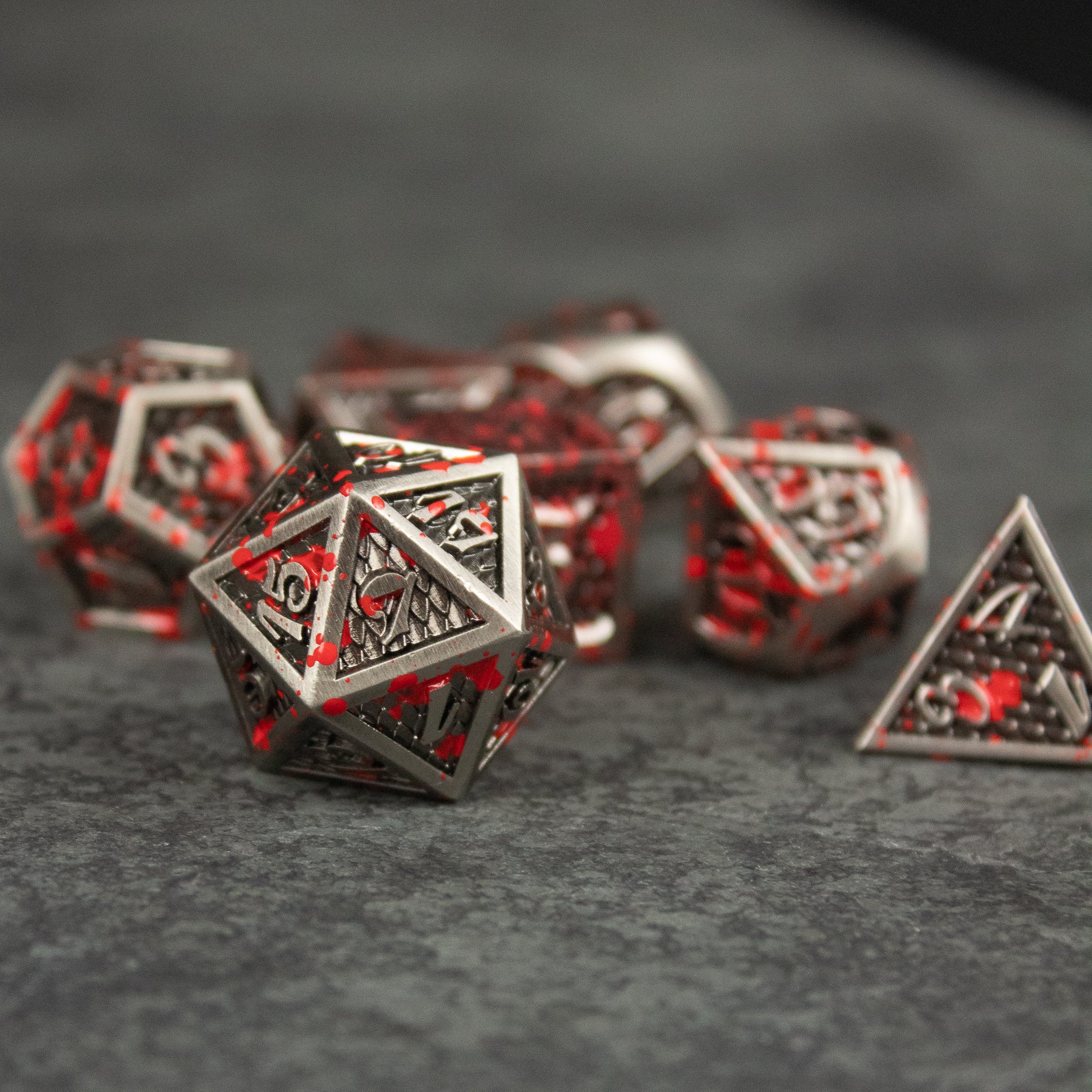 Marauder Dice Set - Metallic dungeon dice set with red numbering, featuring multiple polyhedral shapes including a 20-sided die.