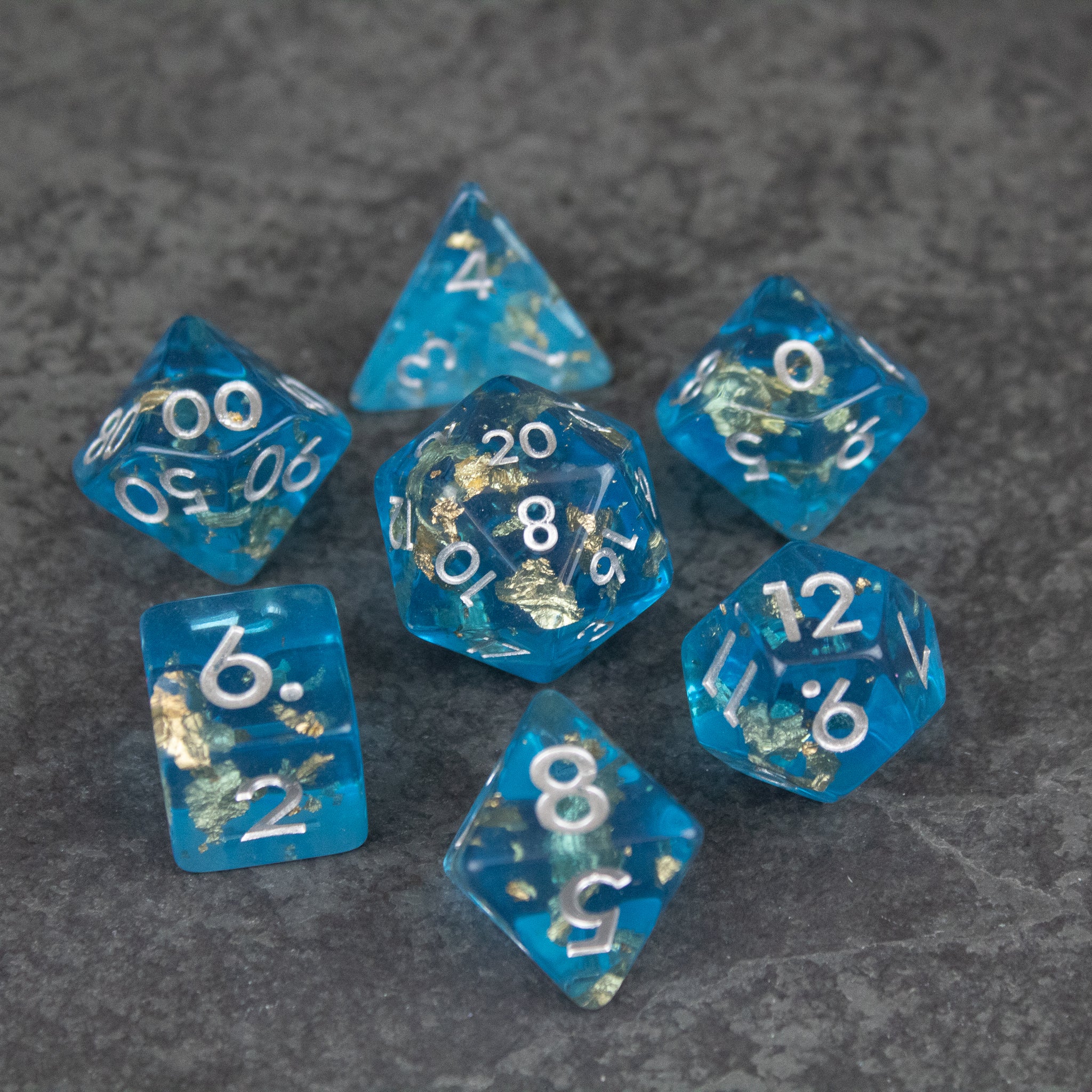 Blue Foil Dice Set - Set of seven translucent blue polyhedral dice with white numbers and metallic foil flakes inside.