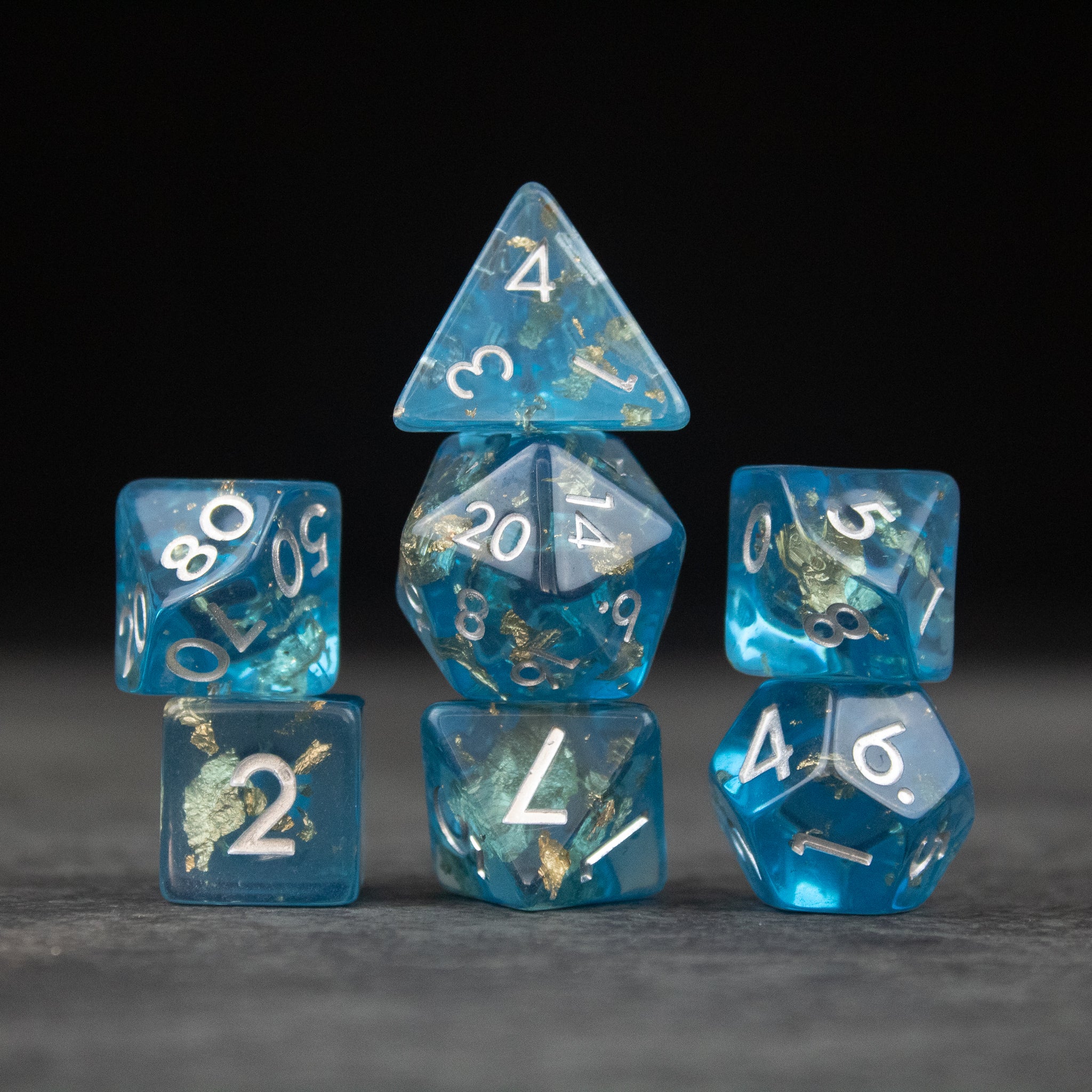 Blue Foil Dice Set - Seven blue translucent dice with silver foil inclusions and white numbering, including d4, d6, d8, d10, d12, and d20 shapes.