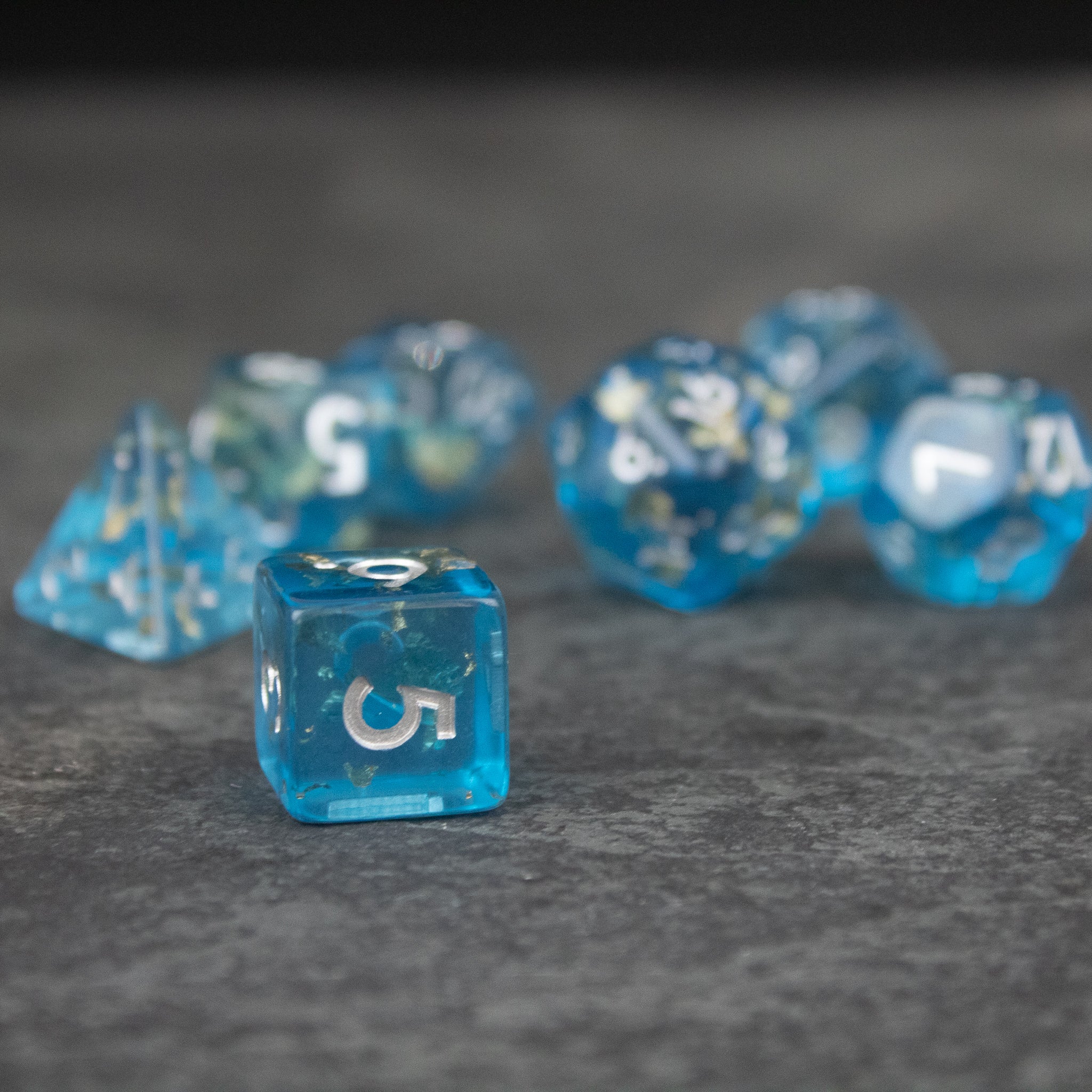 Blue Foil Dice Set - Translucent blue foil polyhedral dice set with white numbers on gray surface.