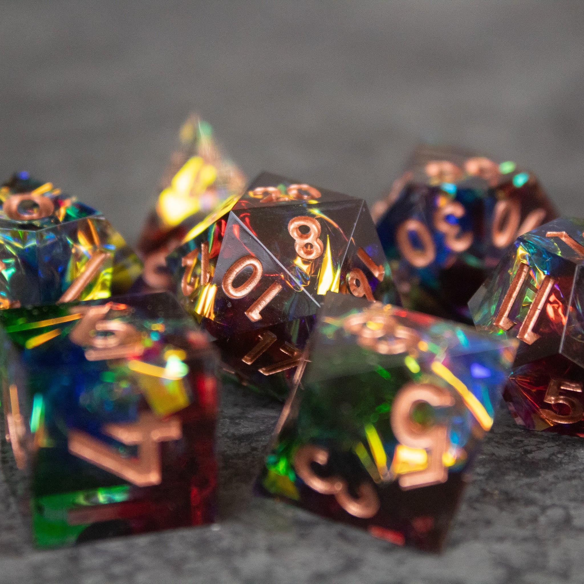 Aurora Dice Set - Sharp-edged translucent polyhedral dice with iridescent rainbow colors and copper numbering.